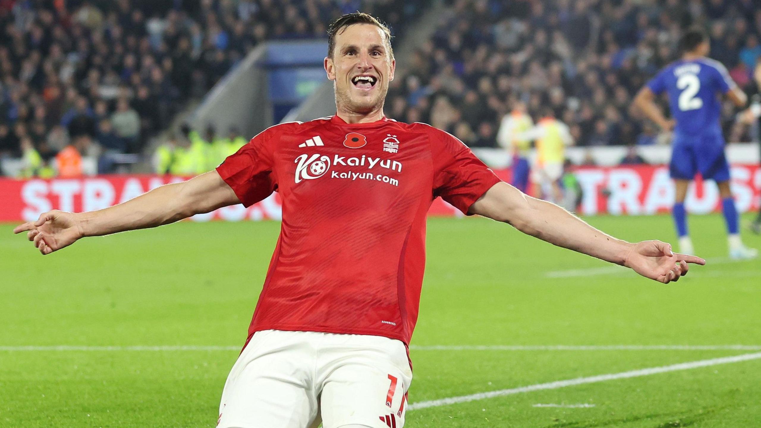 Chris Wood slides on his knees with his arms out in celebration after scoring a second in Nottingham Forest's win at Leicester.