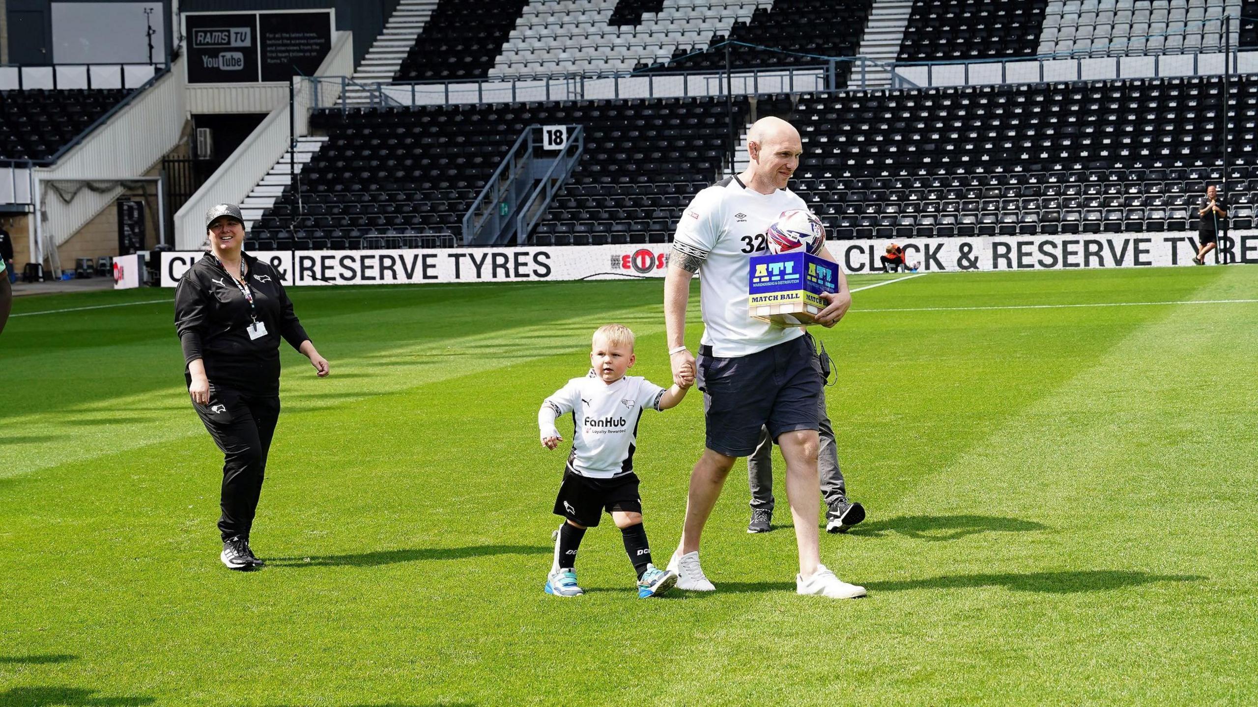 Reuben walks on the pitch at Pride Park with his father Liam carrying the match ball