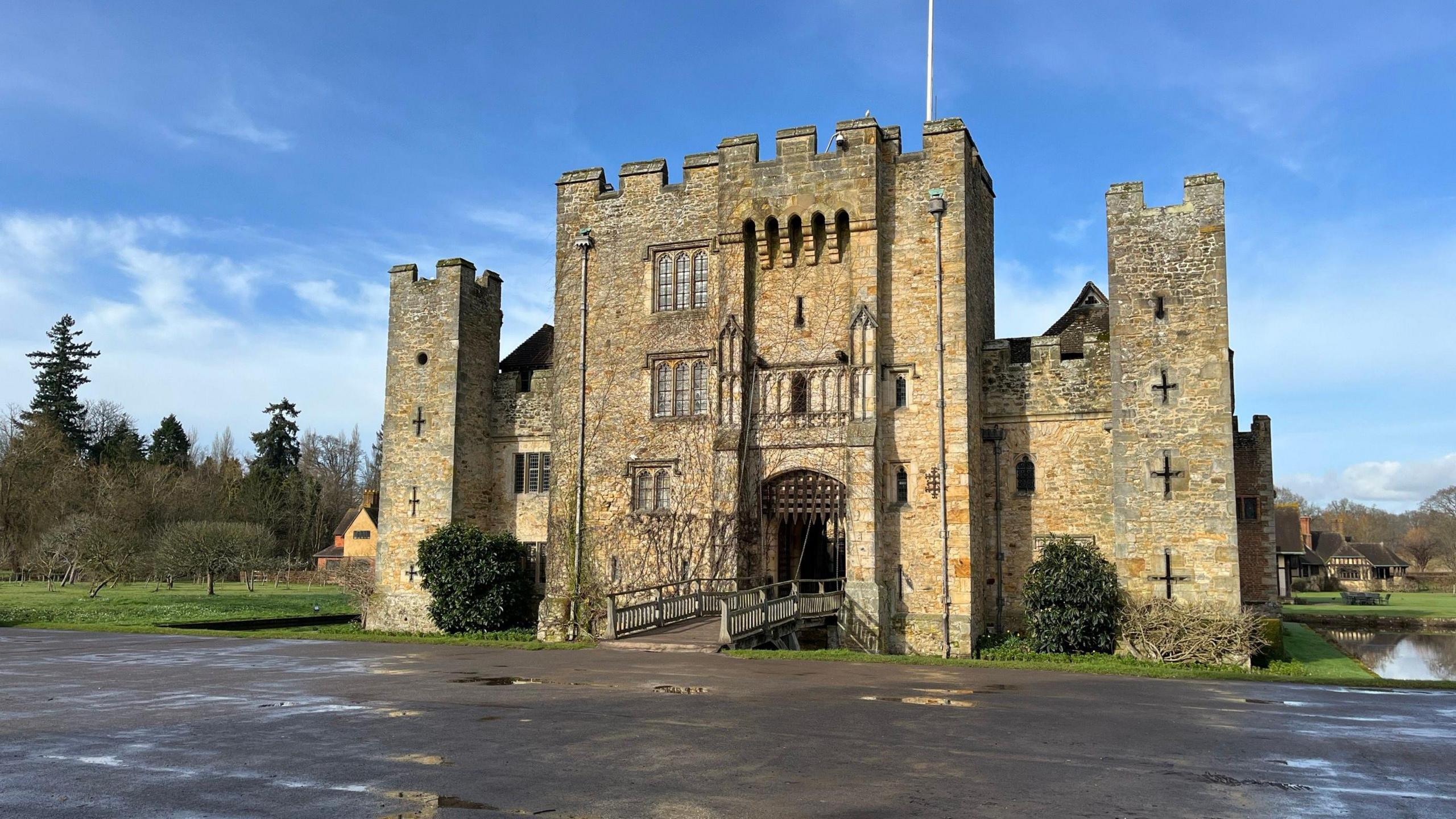 An old castle with yellowy, grey walls on a sunny day. 