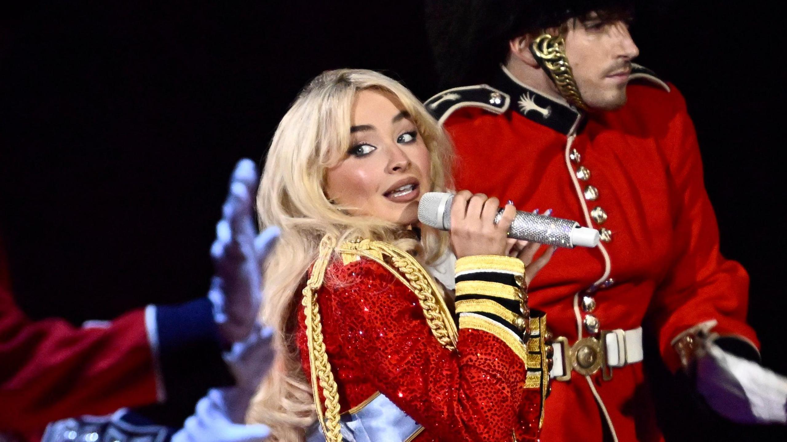 Sabrina Carpenter dancing with a dancer dressed as one of the King's Foot Guards