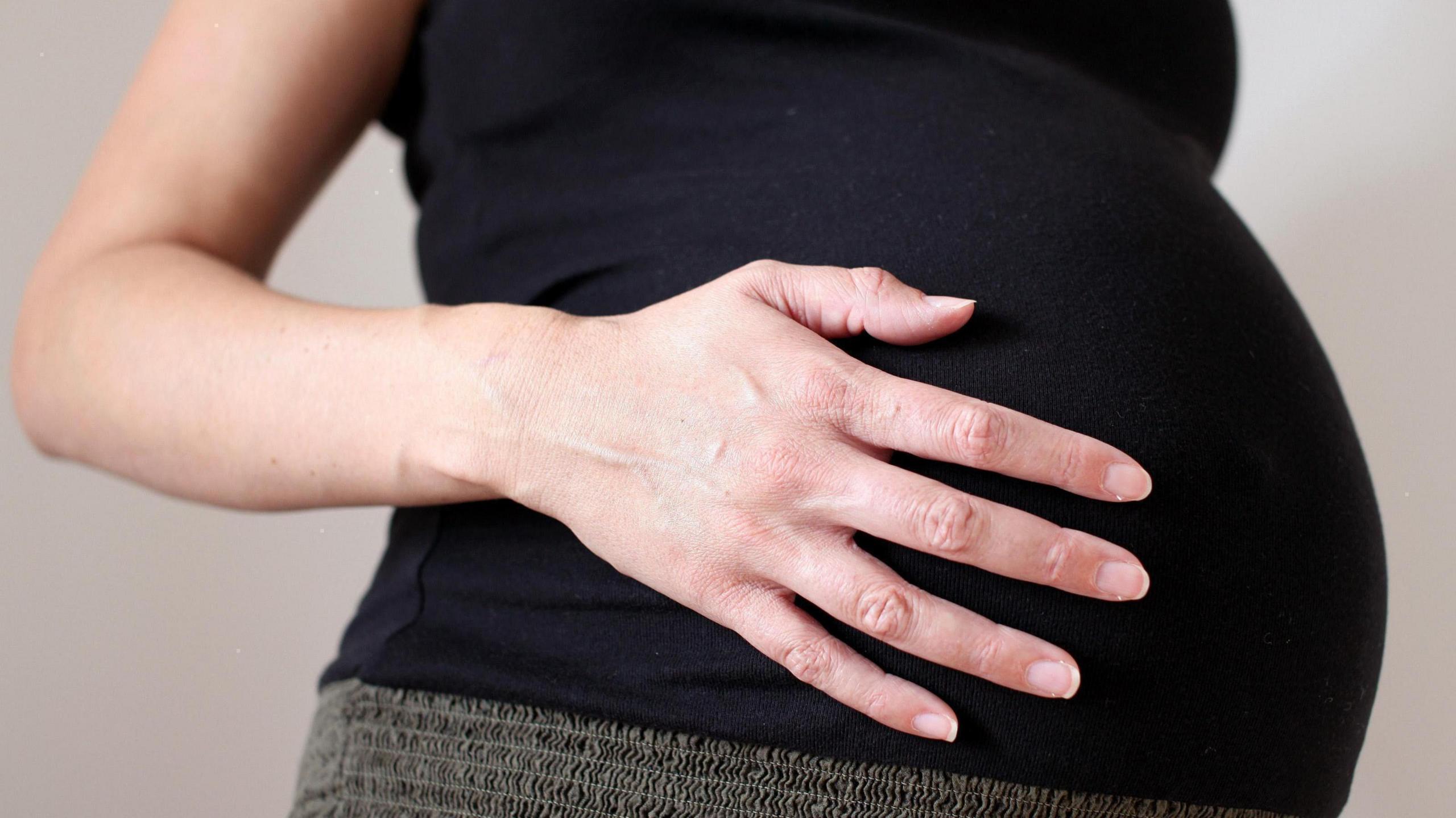 A pregnant woman holding her stomach