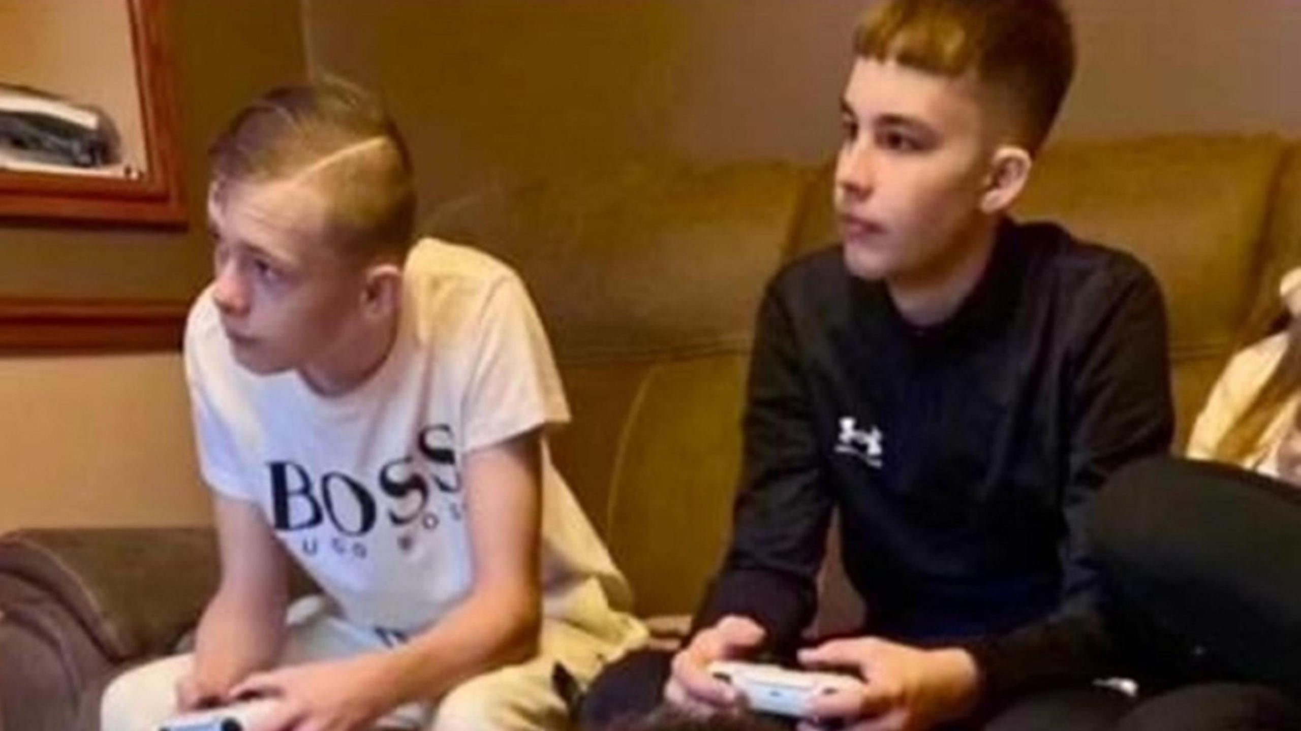 Max and Mason playing computer games, sitting on a brown sofa