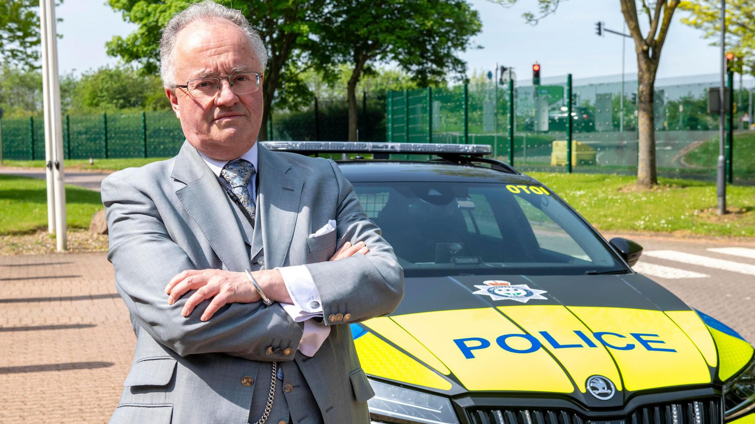 Rupert Matthews pictured in front of a police car