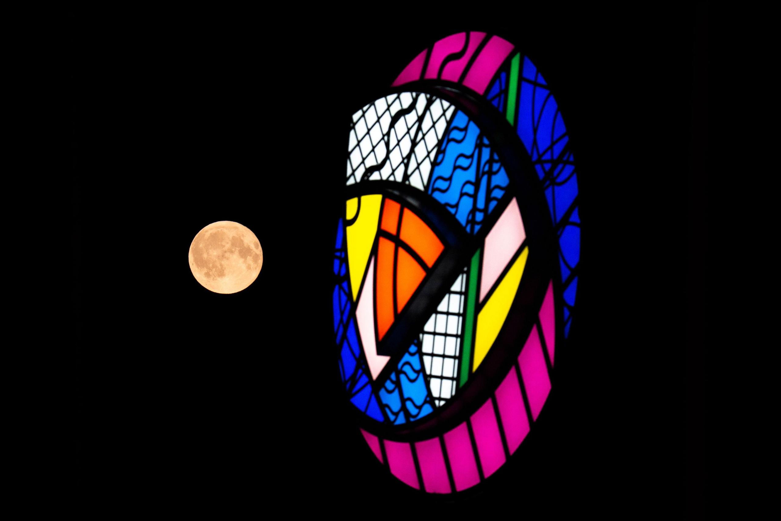 The Full Buck supermoon rises behind the Commonwealth Games Art Deco rose artwork, by artist Emer Tumilty, suspended from the Finnieston Crane in Glasgow. Male deer, who shed their antlers every year, begin to regrow them in July, hence the Native American name for July's full moon.