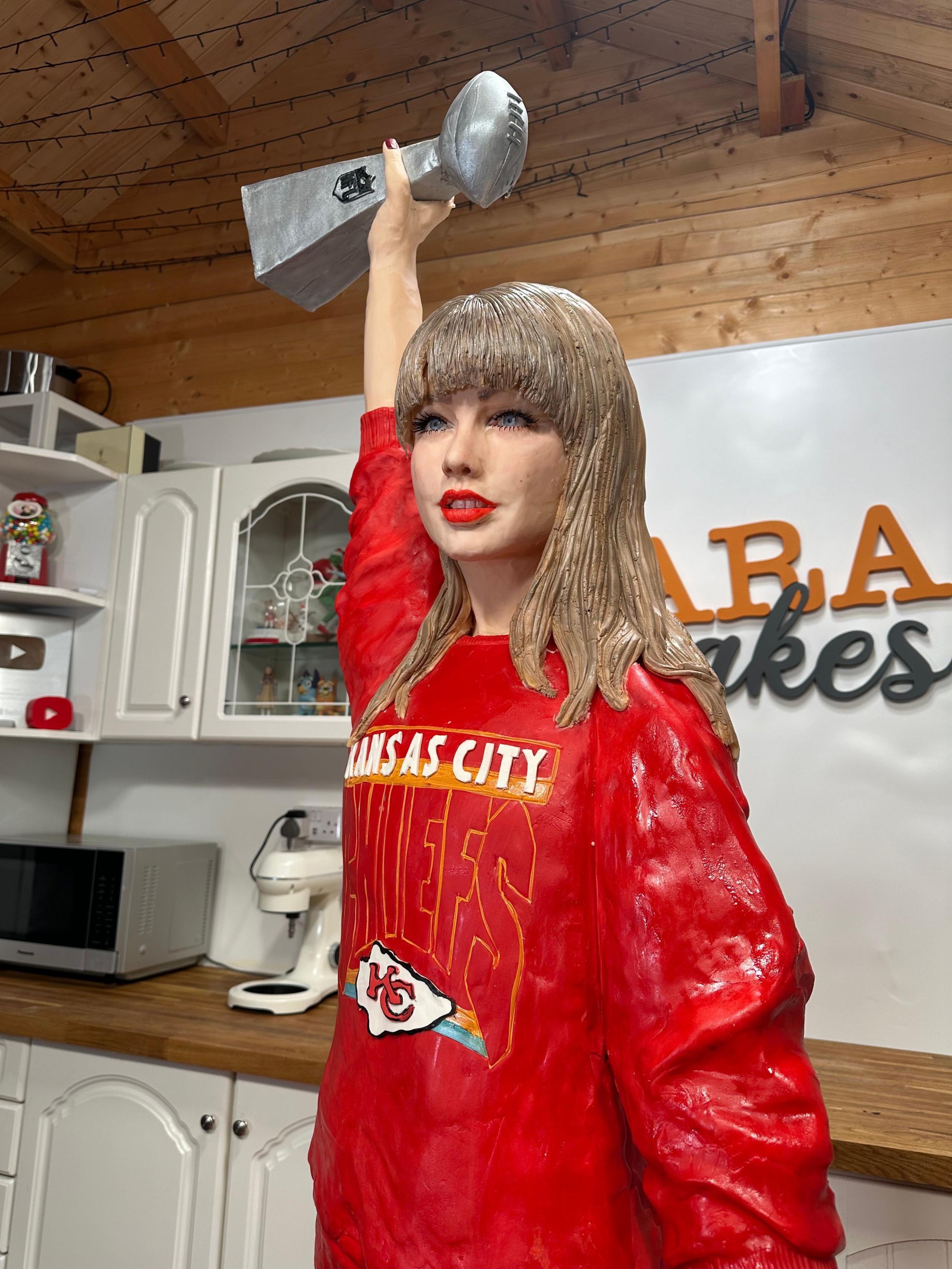 The Taylor Swift cake holding a Super Bowl trophy in the air