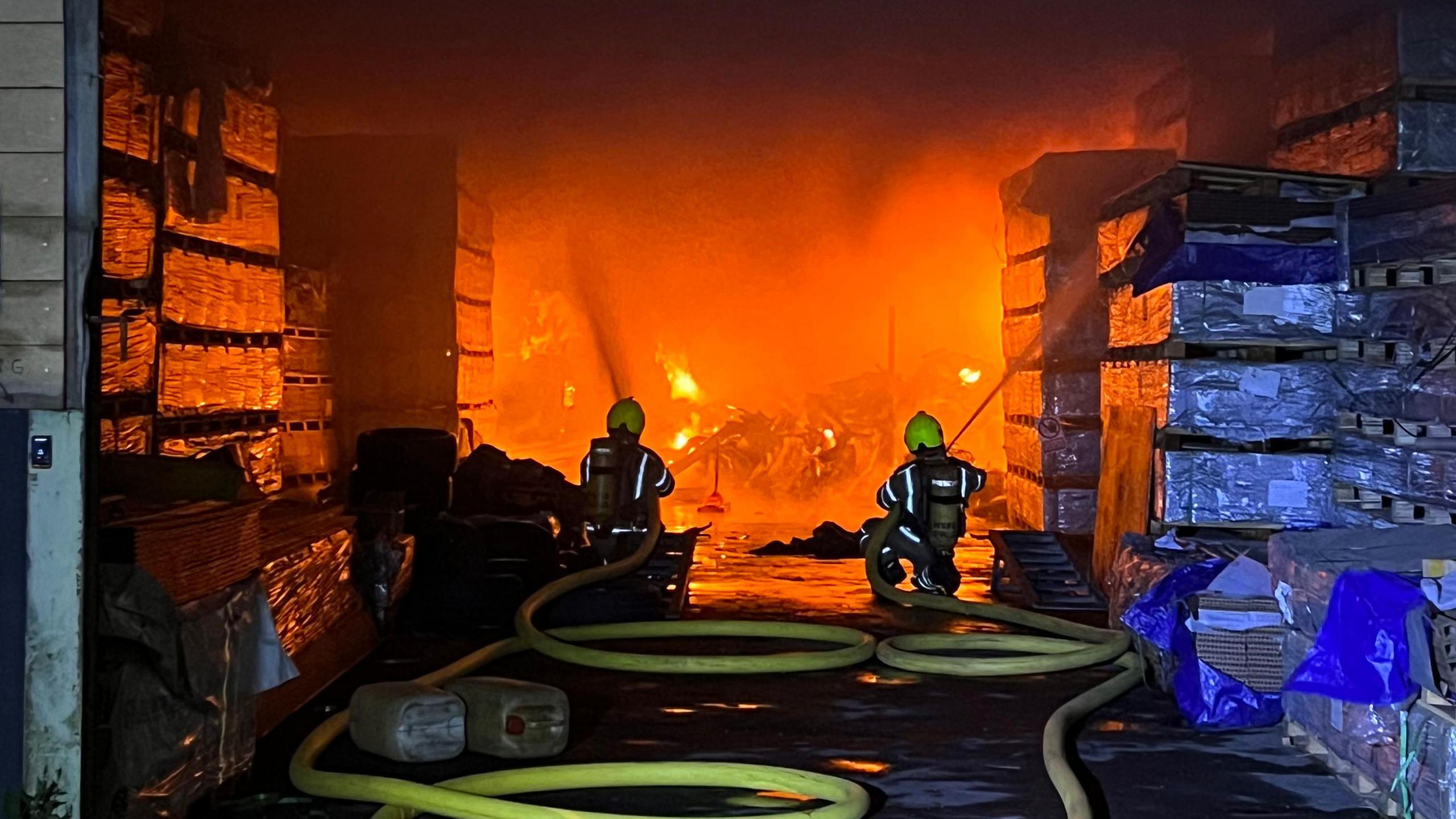 Firefighters tackle the fire which is seen burning inside a building