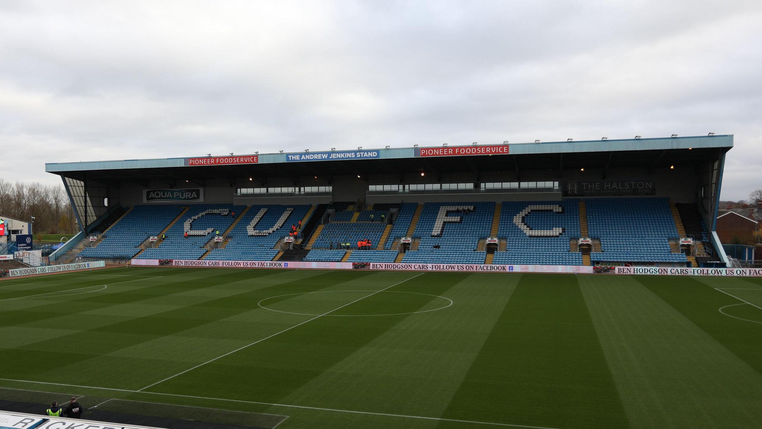 A shot of the pitch and a stand at Carlisle's Brunton Park with the letters 'CUFC' in white on the seats