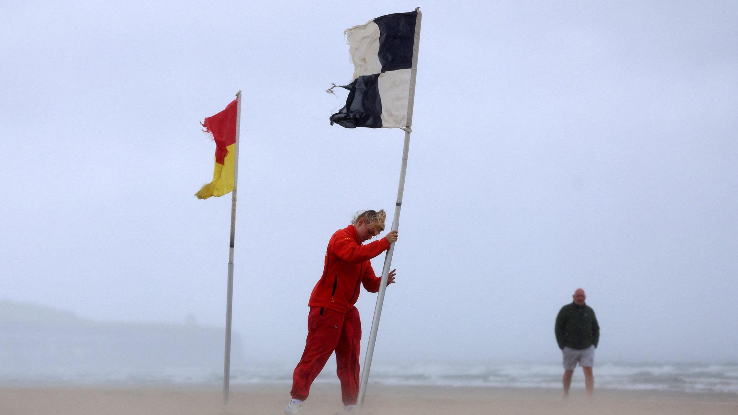 A lifeguard erects a flag during Storm Floris on the north coast of Northern Ireland, Portstewart