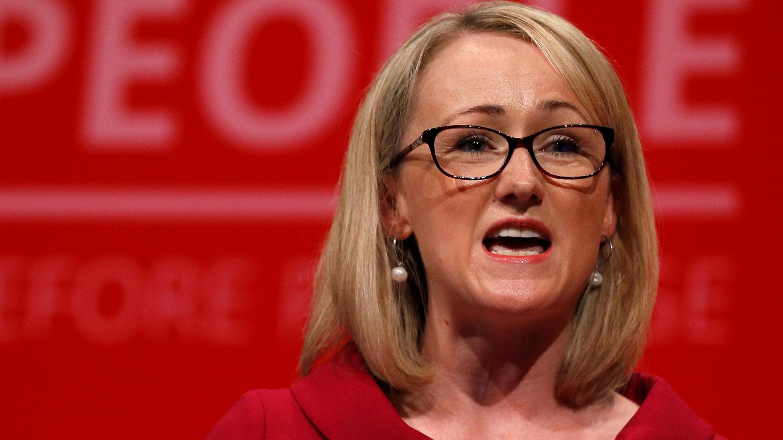 Rebecca Long-Bailey, with black glasses and shoulder-length blonde hair and wearing a red dress, speaks at the Labour party annual conference in Brighton