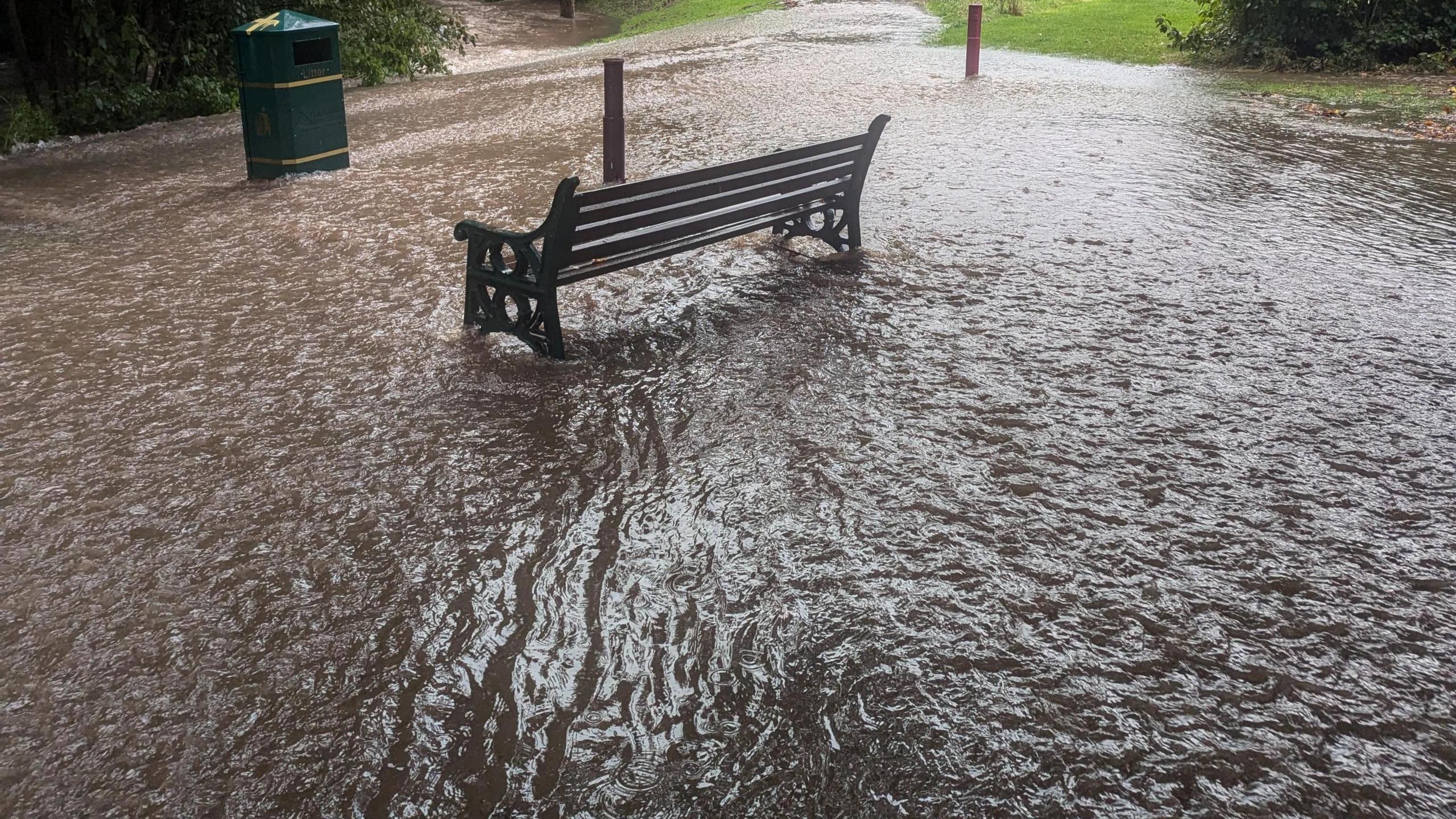 Bench surrounded by water after local stream bursts its bank