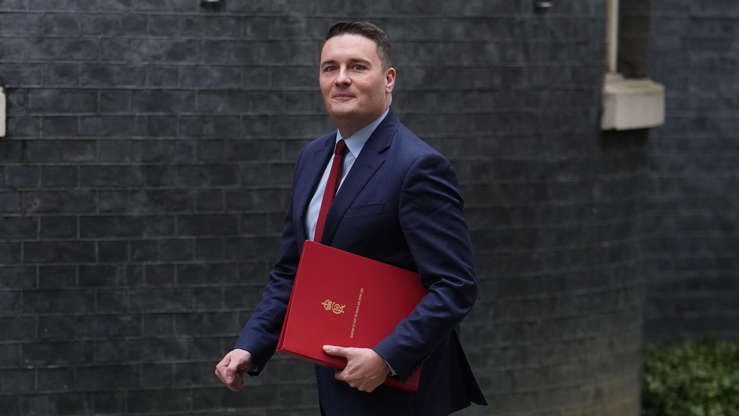 Health Secretary Wes Streeting arriving in Downing Street holding a red ministerial folder.