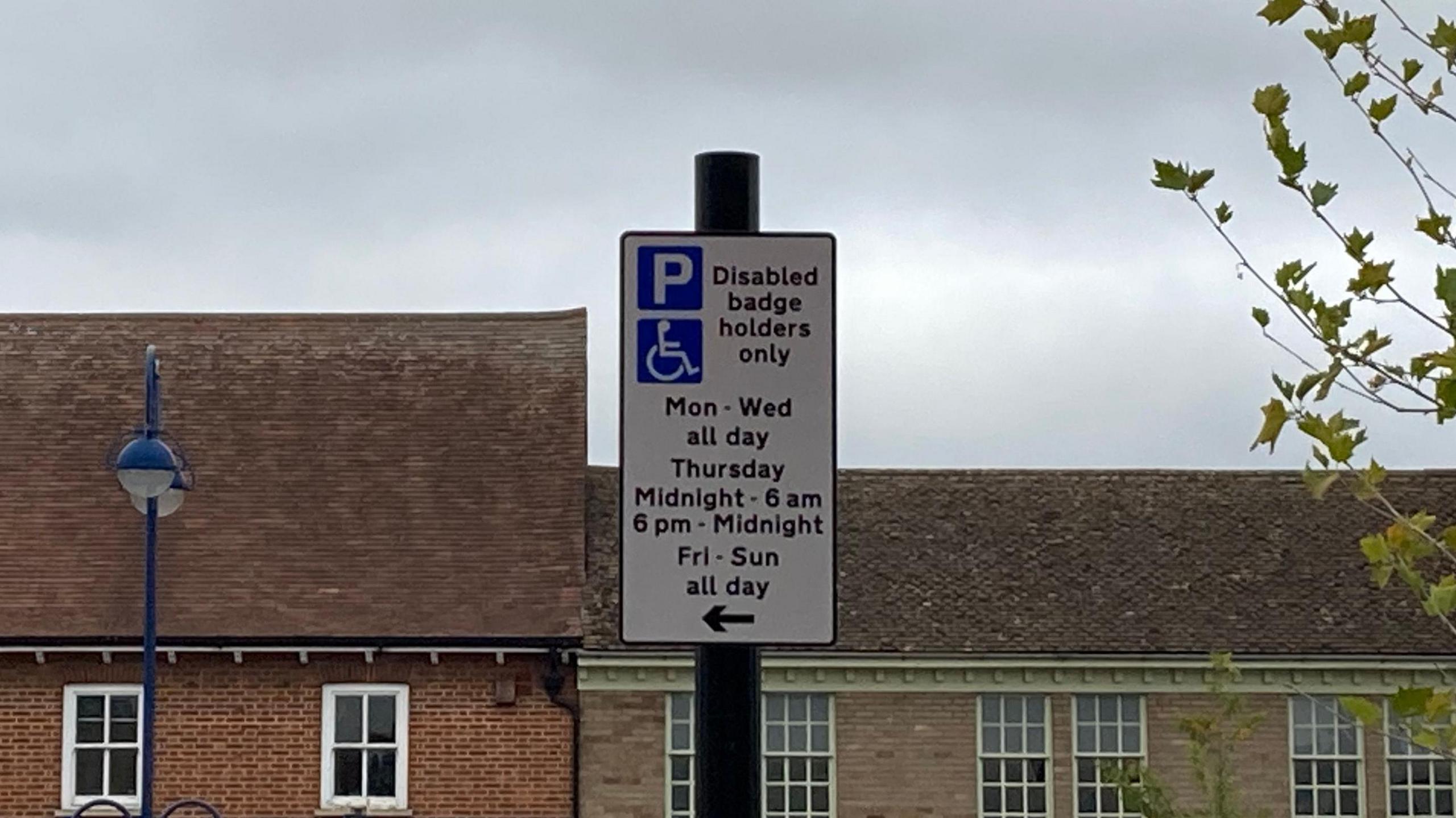A close up of a road sign. It says "Disabled badge holders only, Mon - Wed all day. Thursday Midnight - 6am. 6pm - Midnight. Fri - Sun all day.