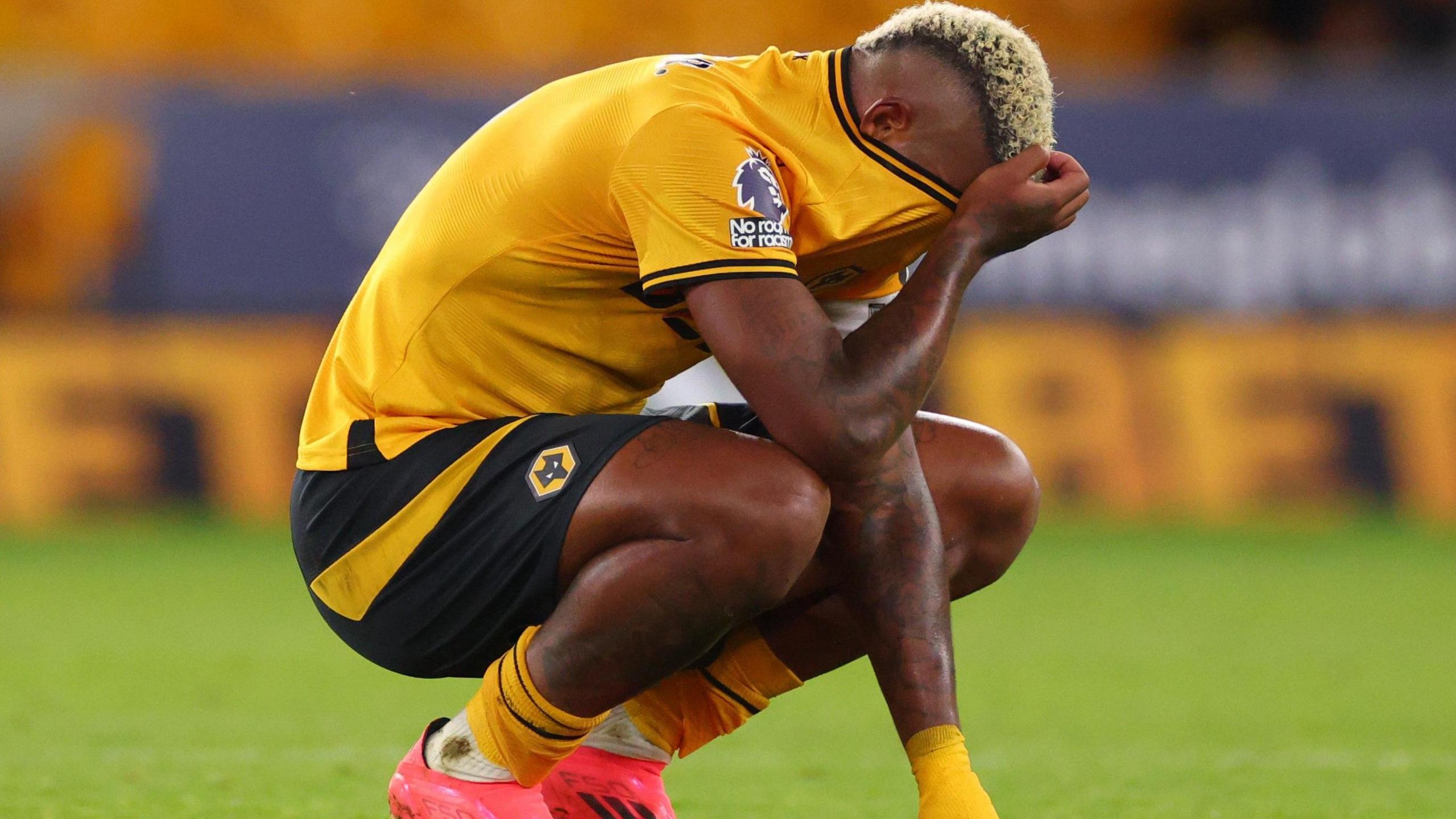 Mario Lemina squads on the Molineux pitch and puts his shirt over his head after defeat by Liverpool. 