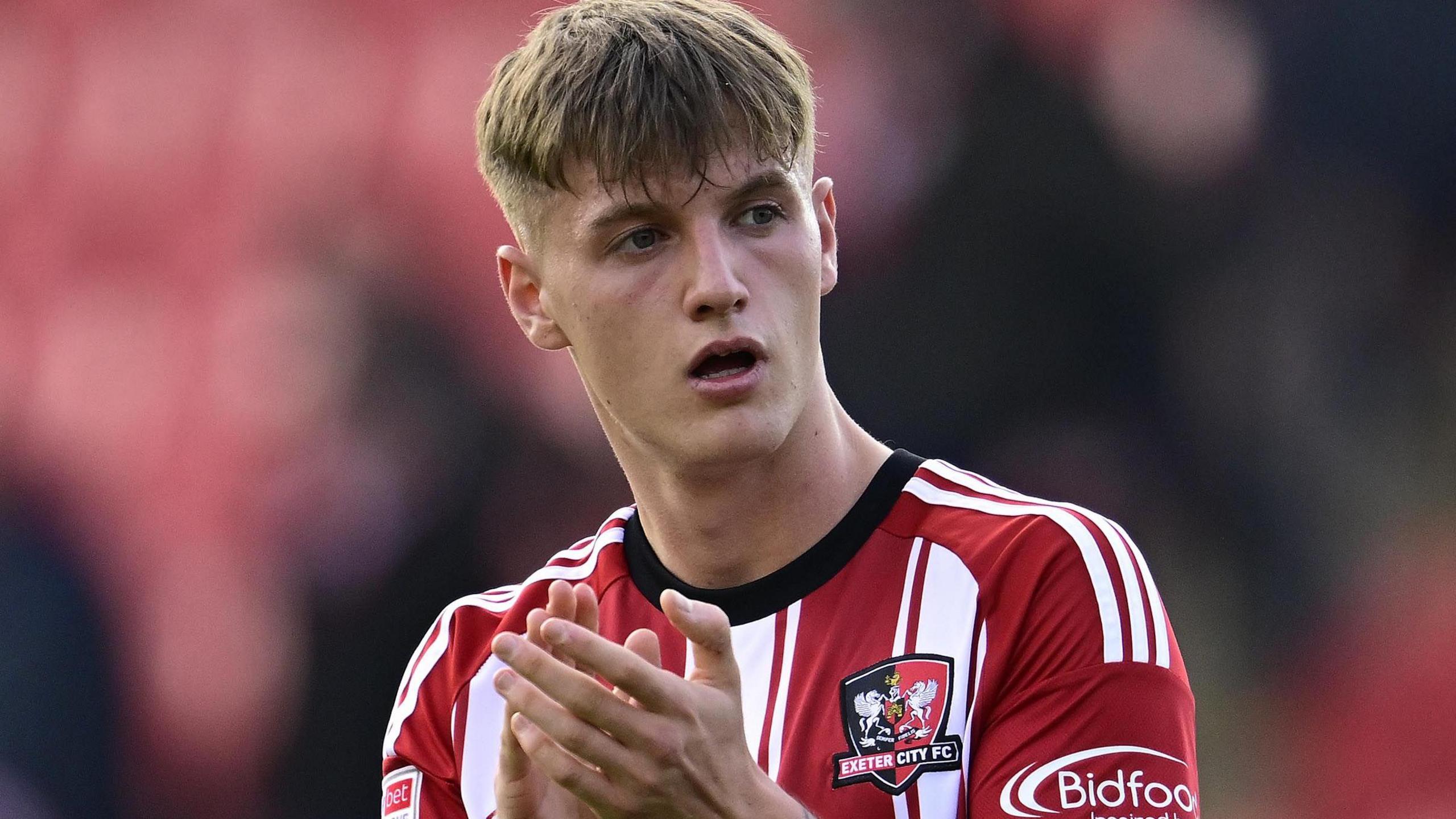Kieran Wilson claps while wearing an Exeter kit