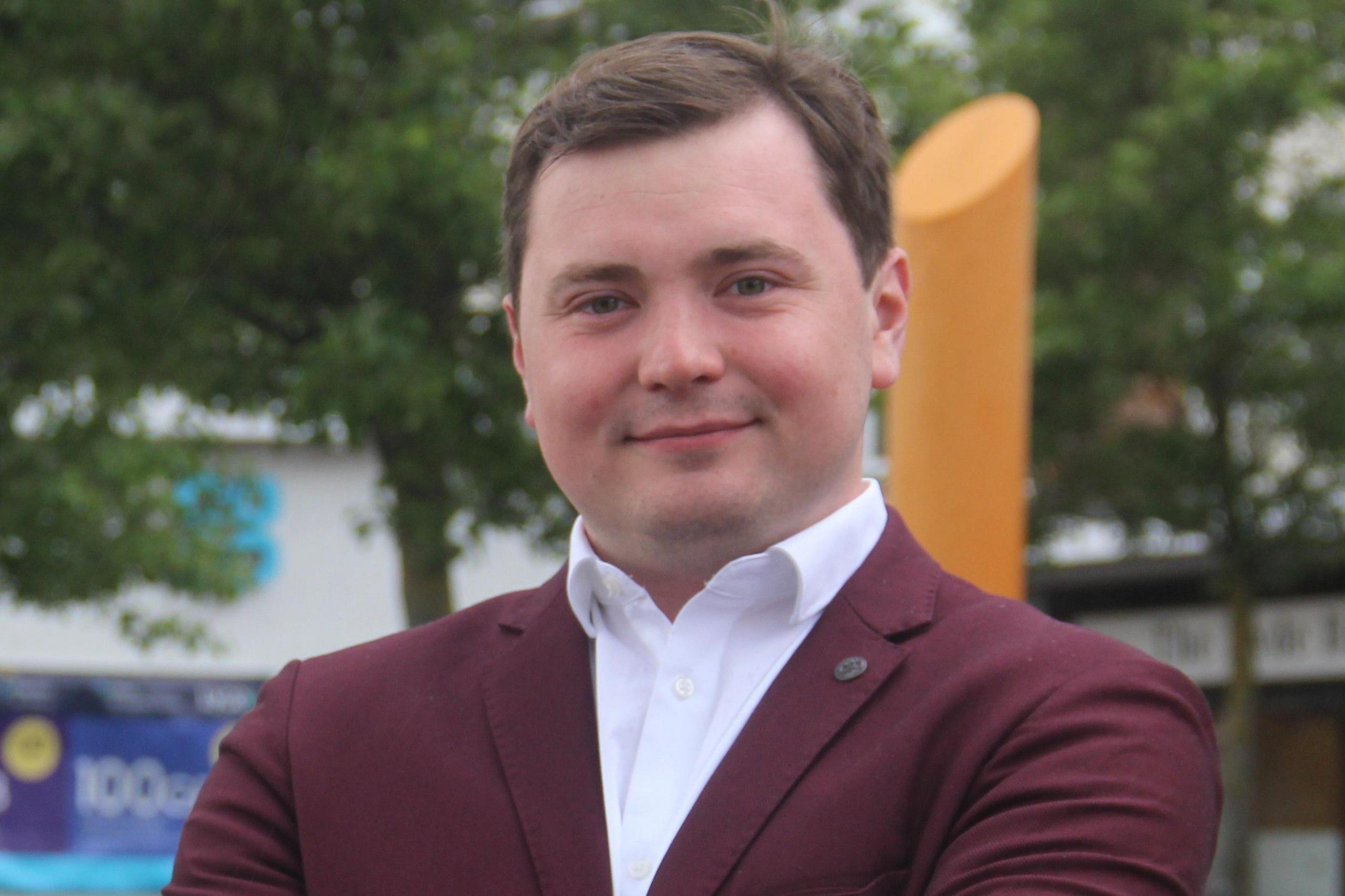 Labour candidate Tom Plater in a burgundy-coloured suit and white open-neck shirt