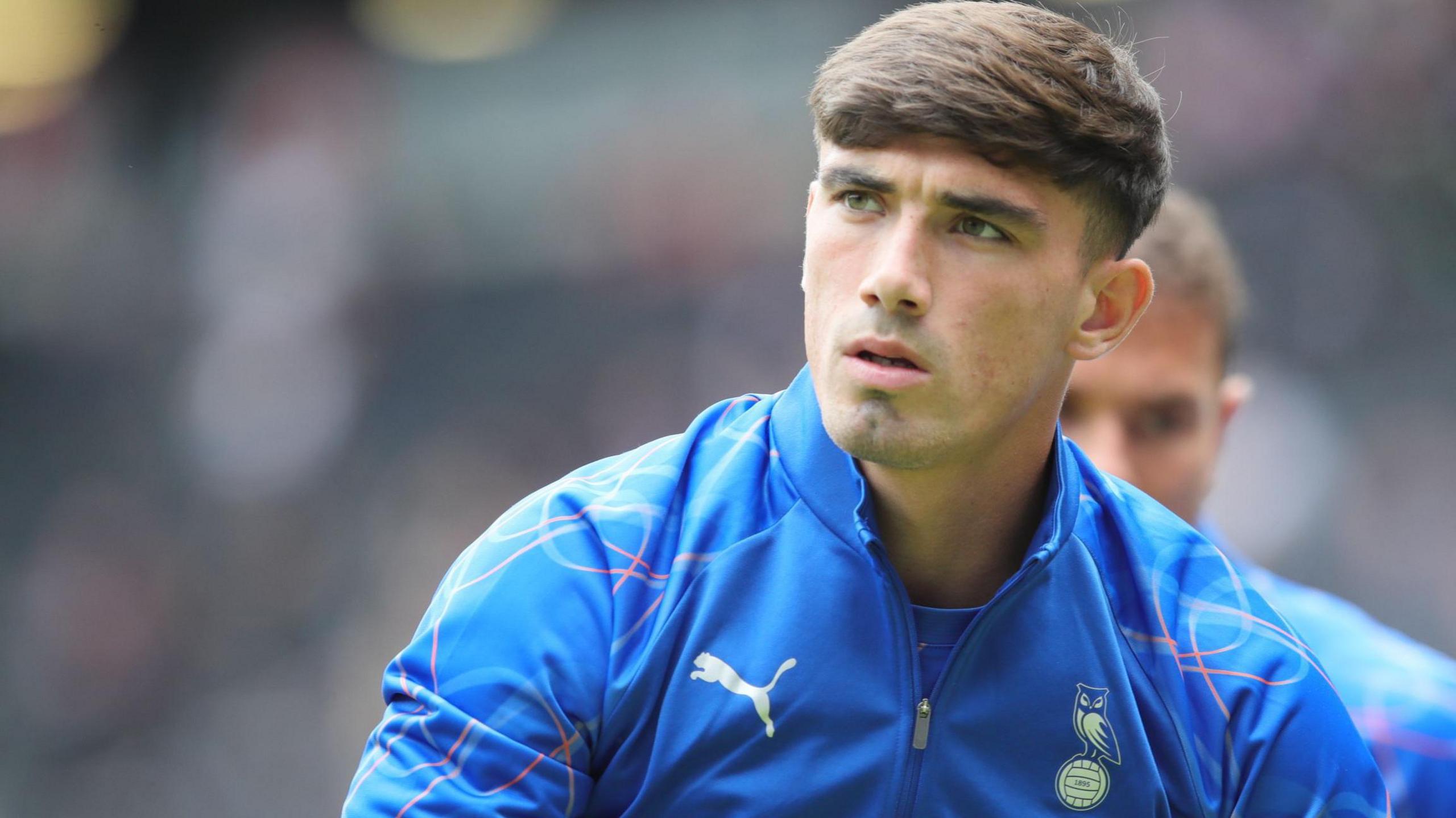 Kian Harratt wearing a blue Oldham Athletic tracksuit top