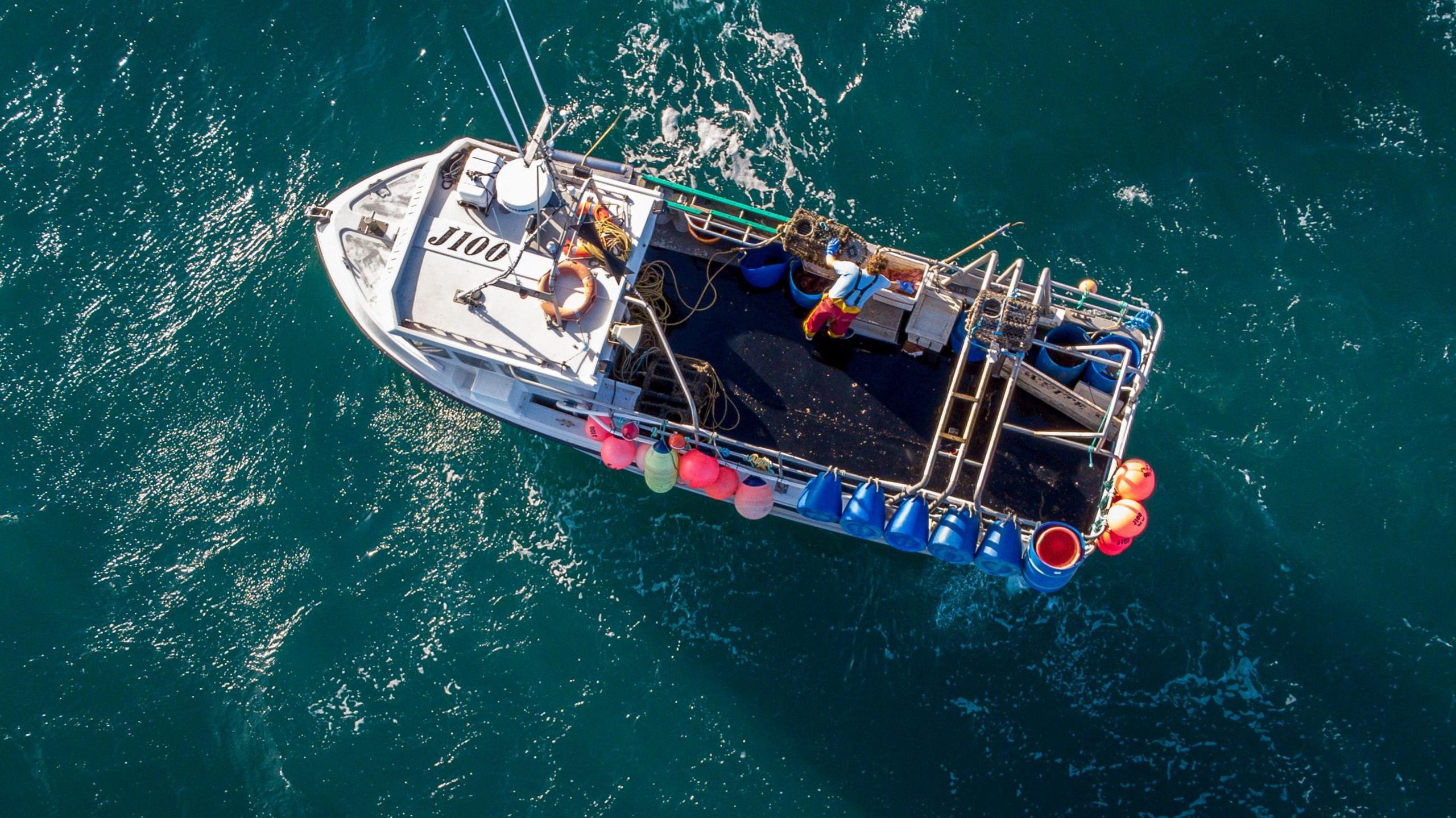Photo of a fisherman landing his catch on a boat in the sea.
