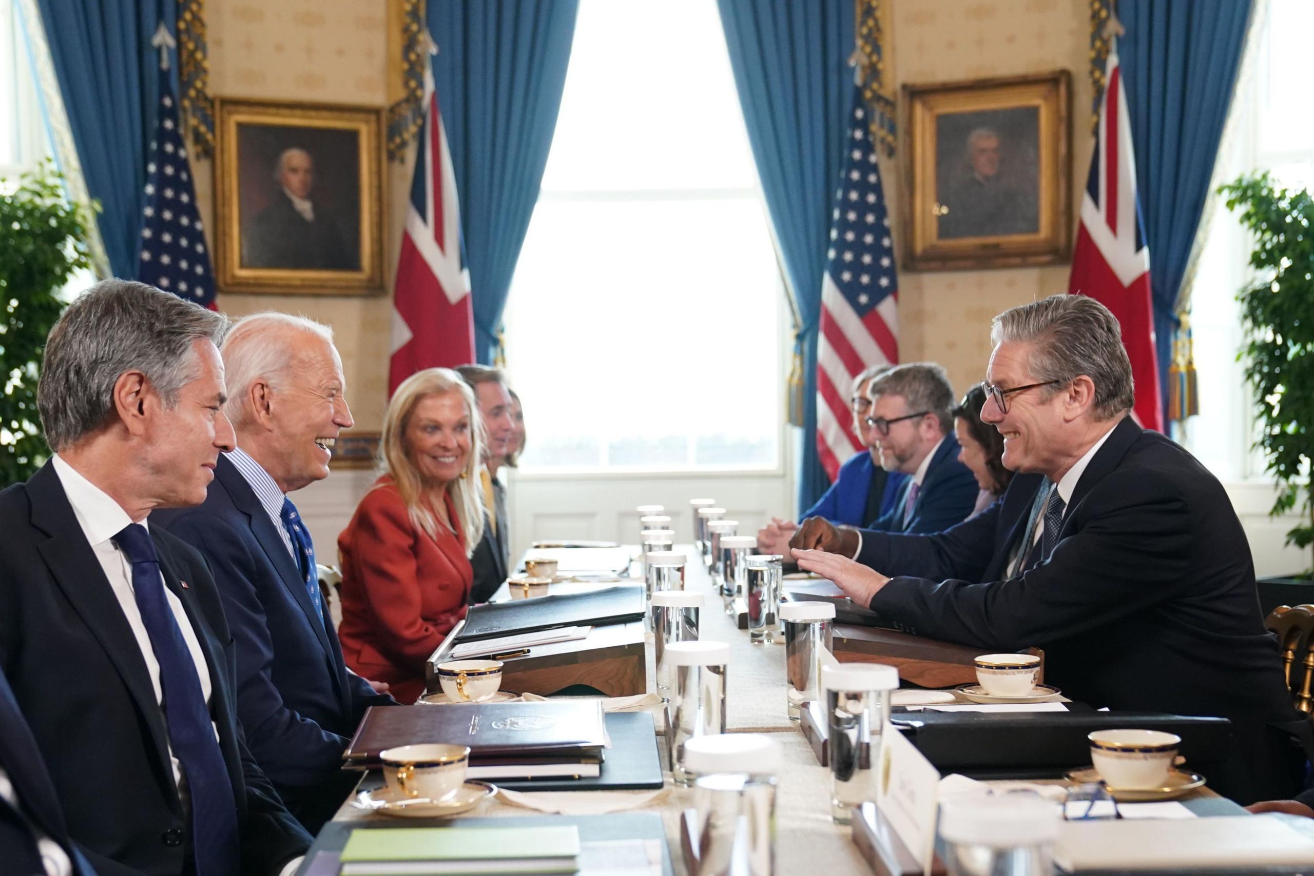 A smiling Prime Minister Sir Keir Starmer sits across the table during a meeting with US President Joe Biden in the Blue Room at the White House in Washington DC