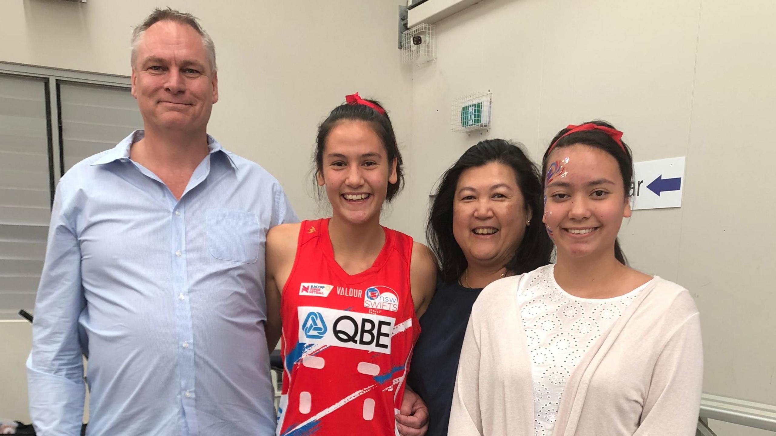Family picture showing Sophie Fawns in red NSW Swifts netball outfit, with father Greg in blue shirt, mother Maureen in dark outfit, and sister Katie in cream cardigan and top, with all smiling for the camera