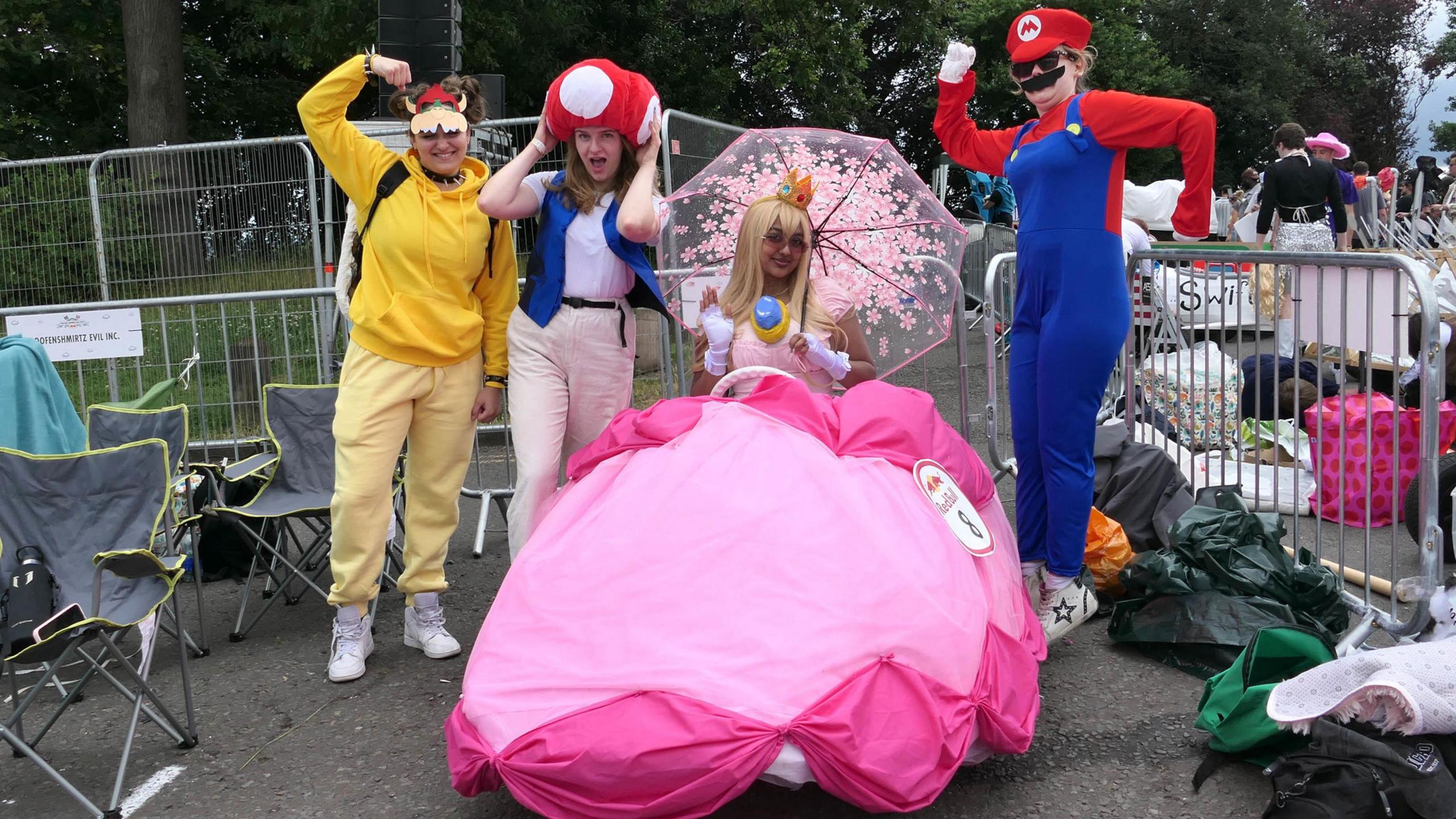 The 12%, dressed as characters from the Mario Bros game, with a woman in a pink kart in the middle