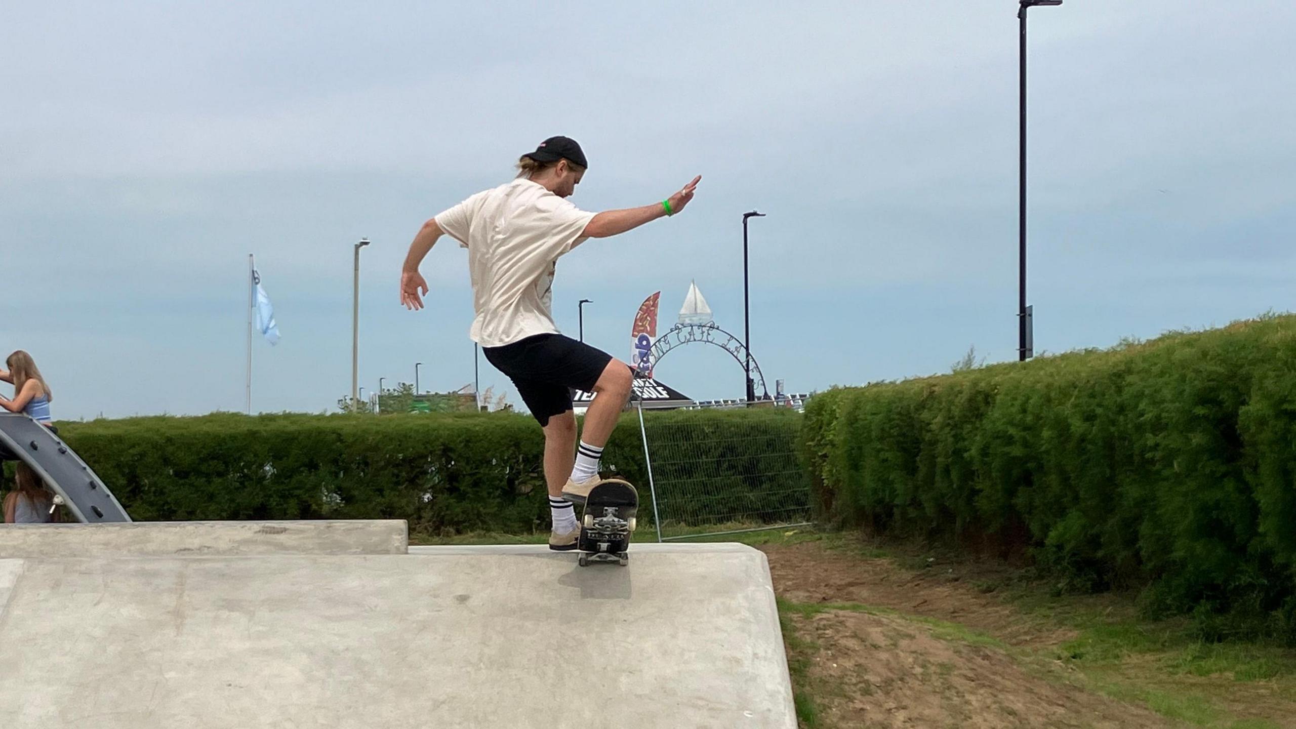 Skateboarder wearing cap and shorts performing a trick at the top of a ramp