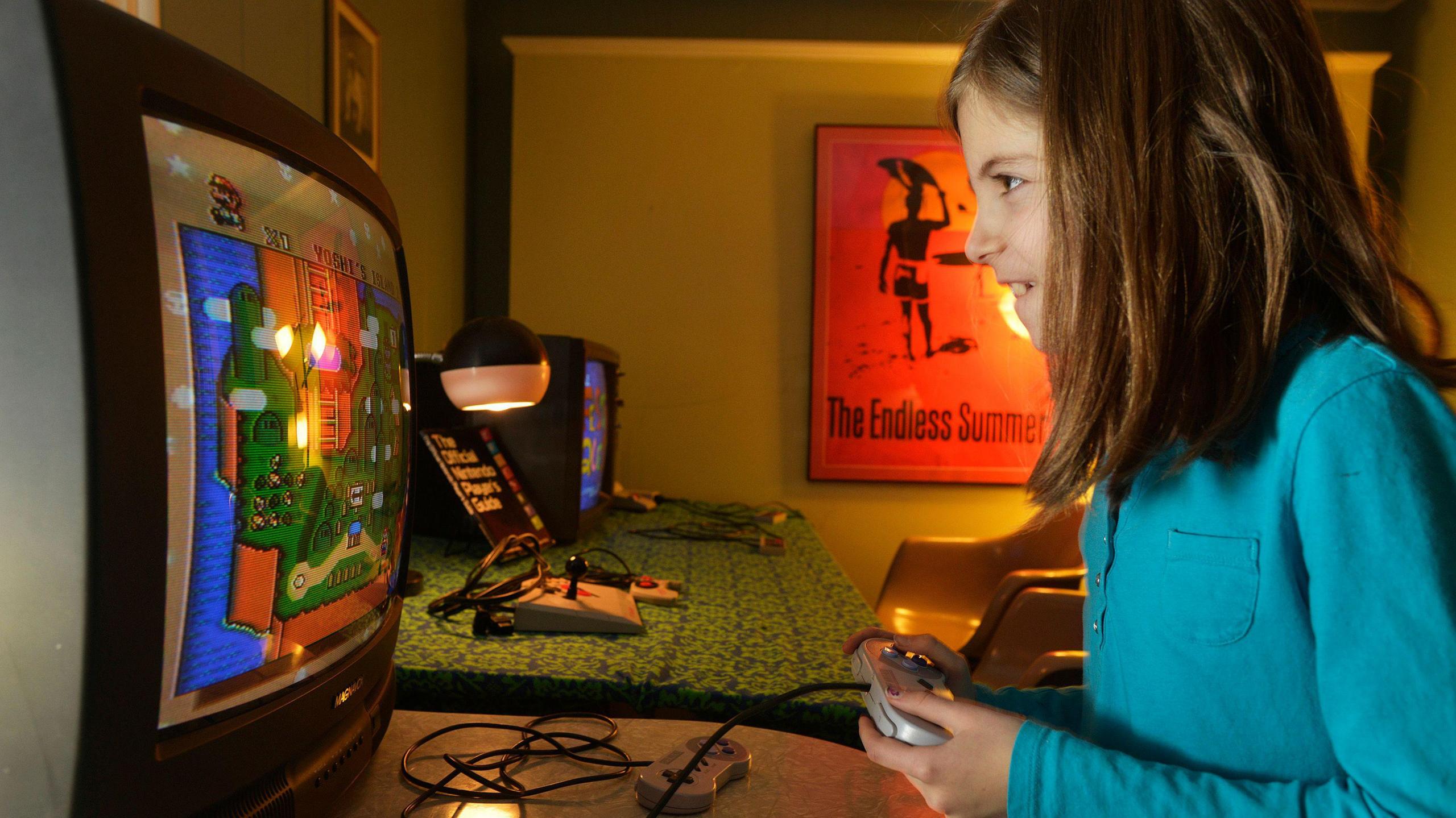 A young child looking intensely at a screen of Super Mario Bros, holding a controller