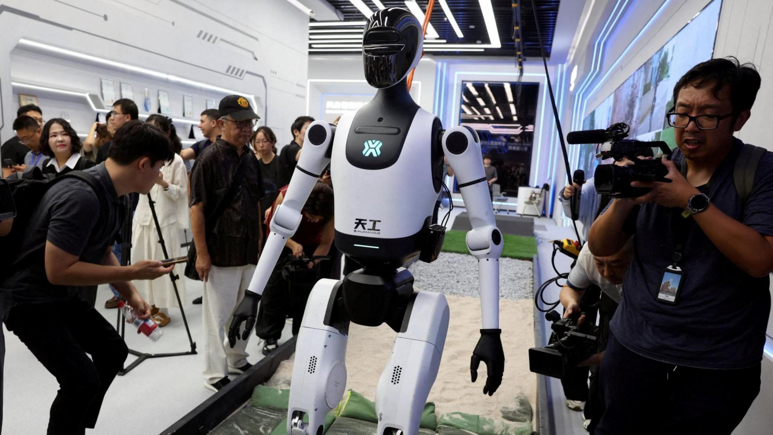 Media members work by a walking Tiangong humanoid robot during an organised media tour to Robot Mall, a store selling humanoid and other robots, in Beijing, China August 6, 2025.