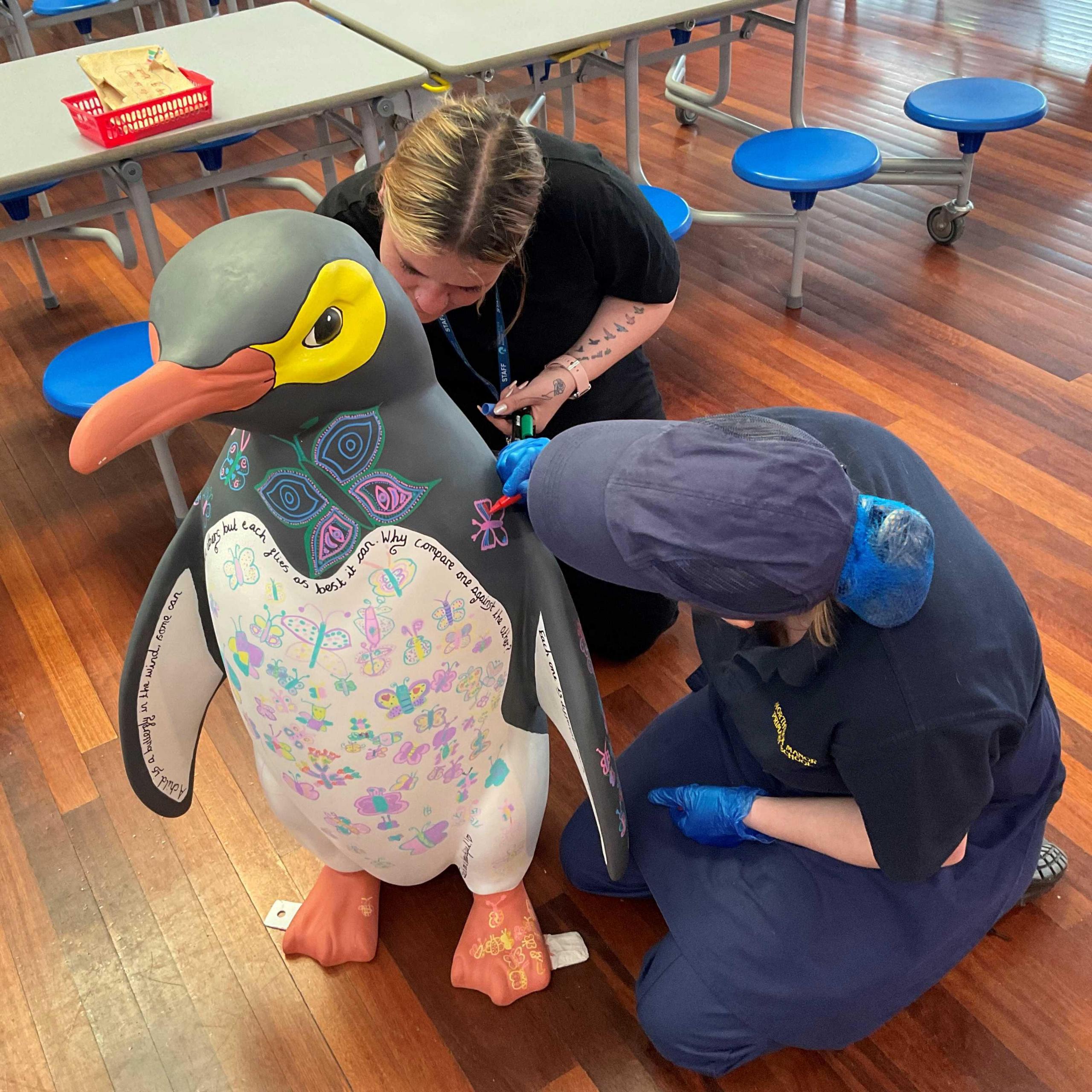 Staff drawing on a giant penguin sculpture 