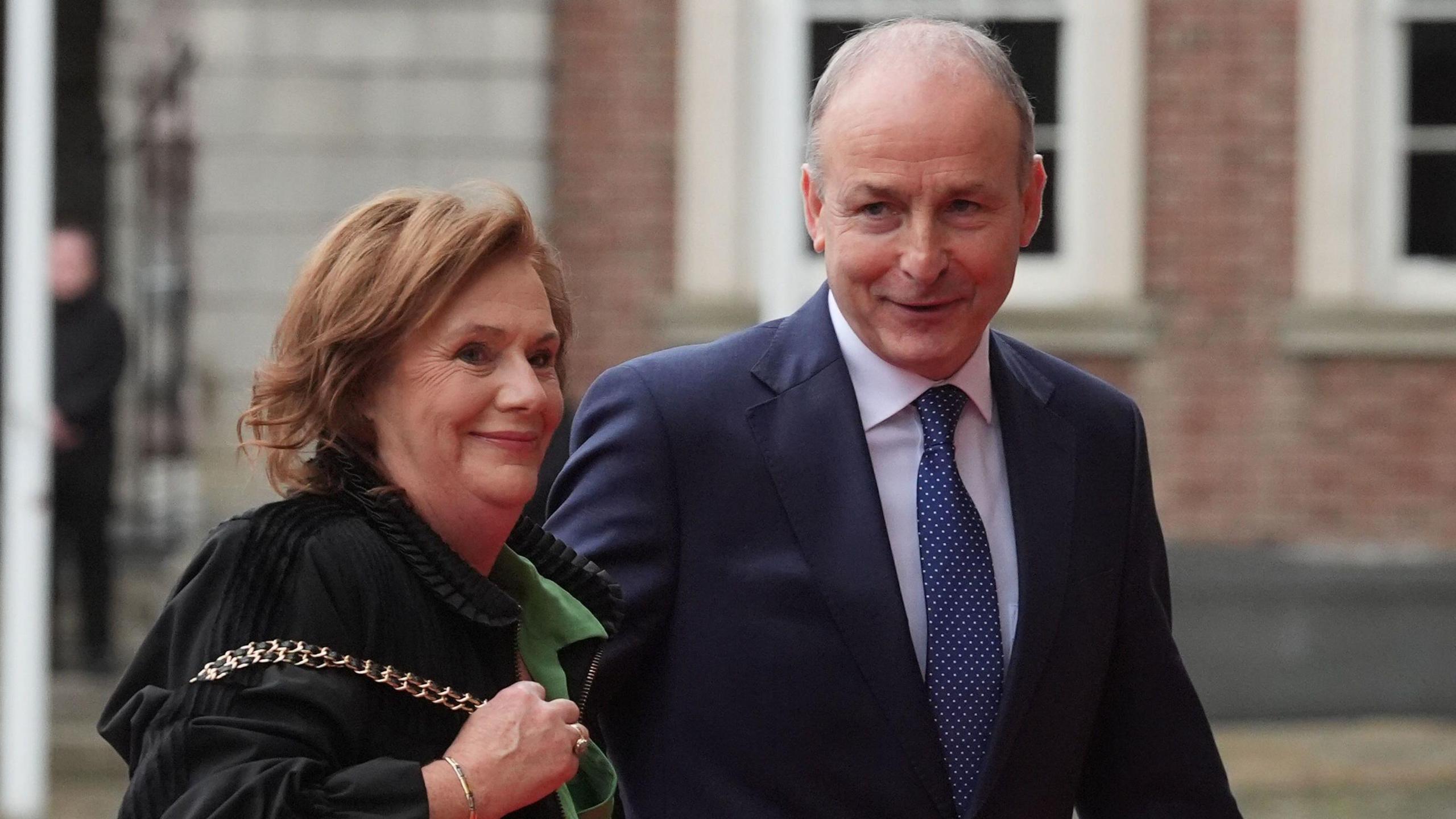 Mary O'Shea wearing a green and black coat, she has dark hair and Micheál Martin , he is wearing a navy suit with navy tie.
