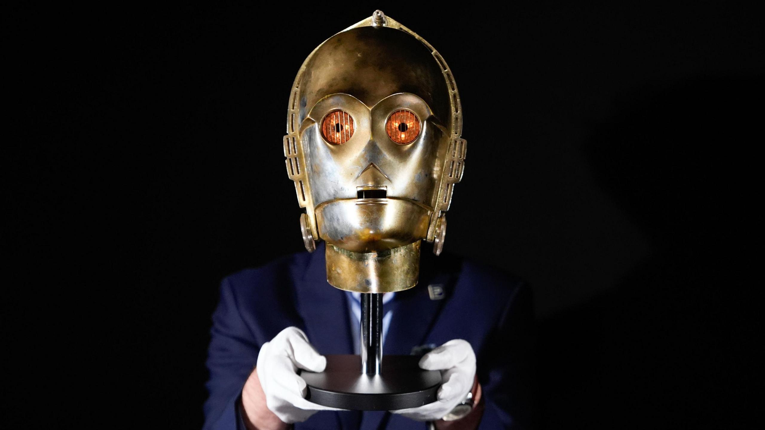 C-3PO head held by auctioneer.