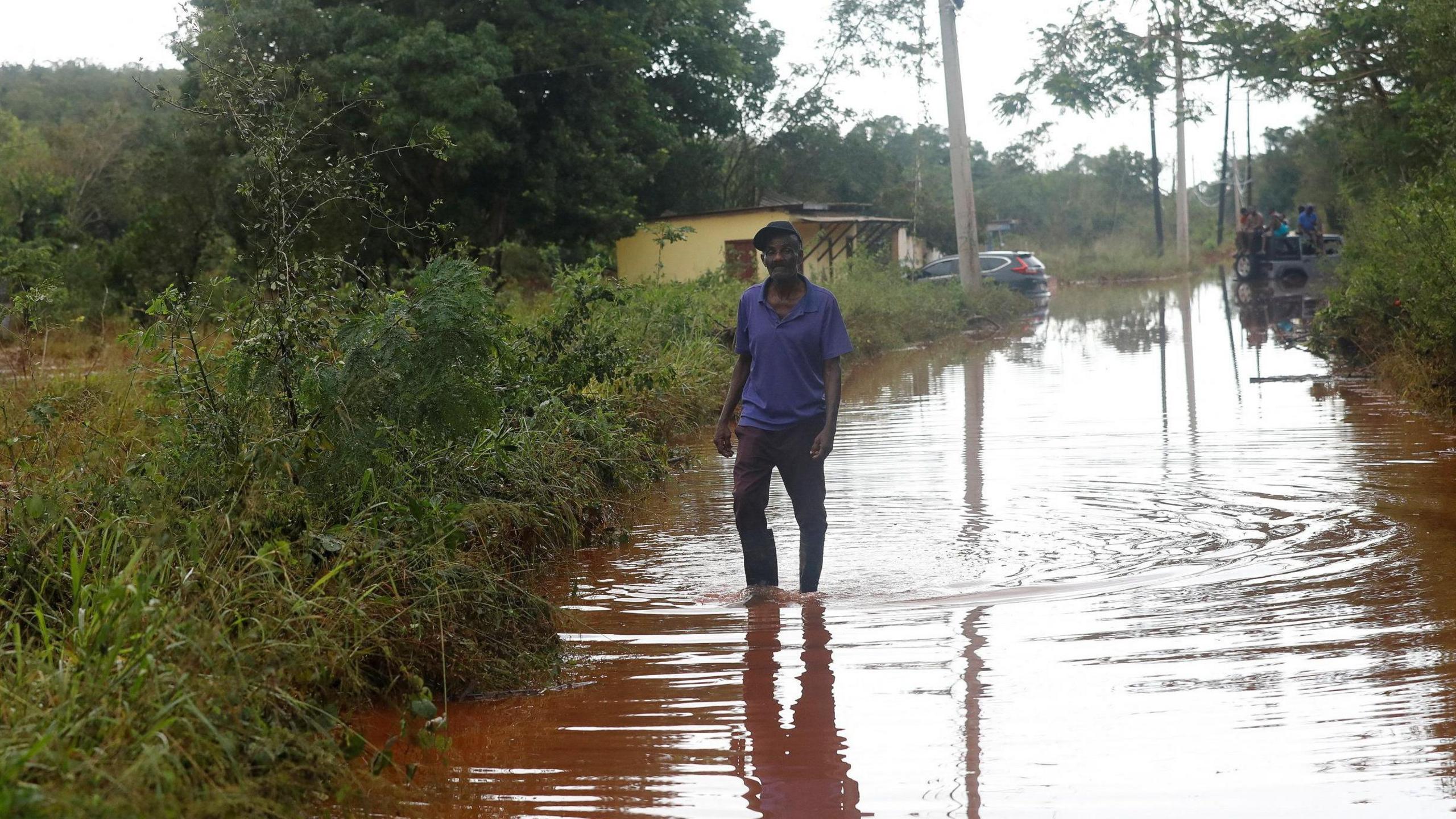 a man walking through a flooded street in Jamaica