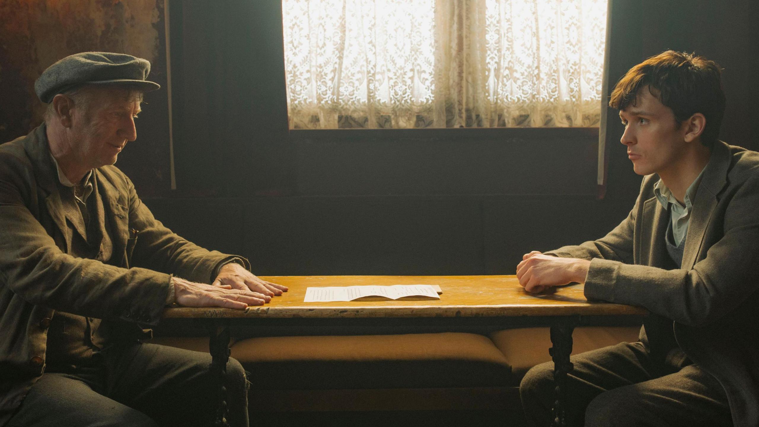 Two sitting at a table, looking at each other