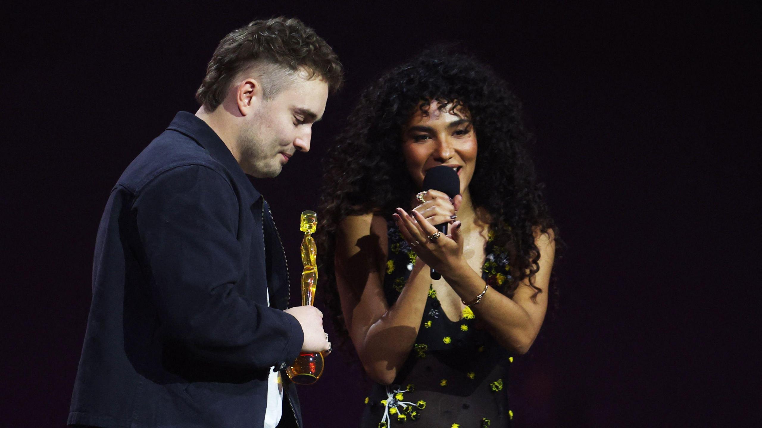 Singers Sam Fender and Olivia Dean collecting an award at the Brits