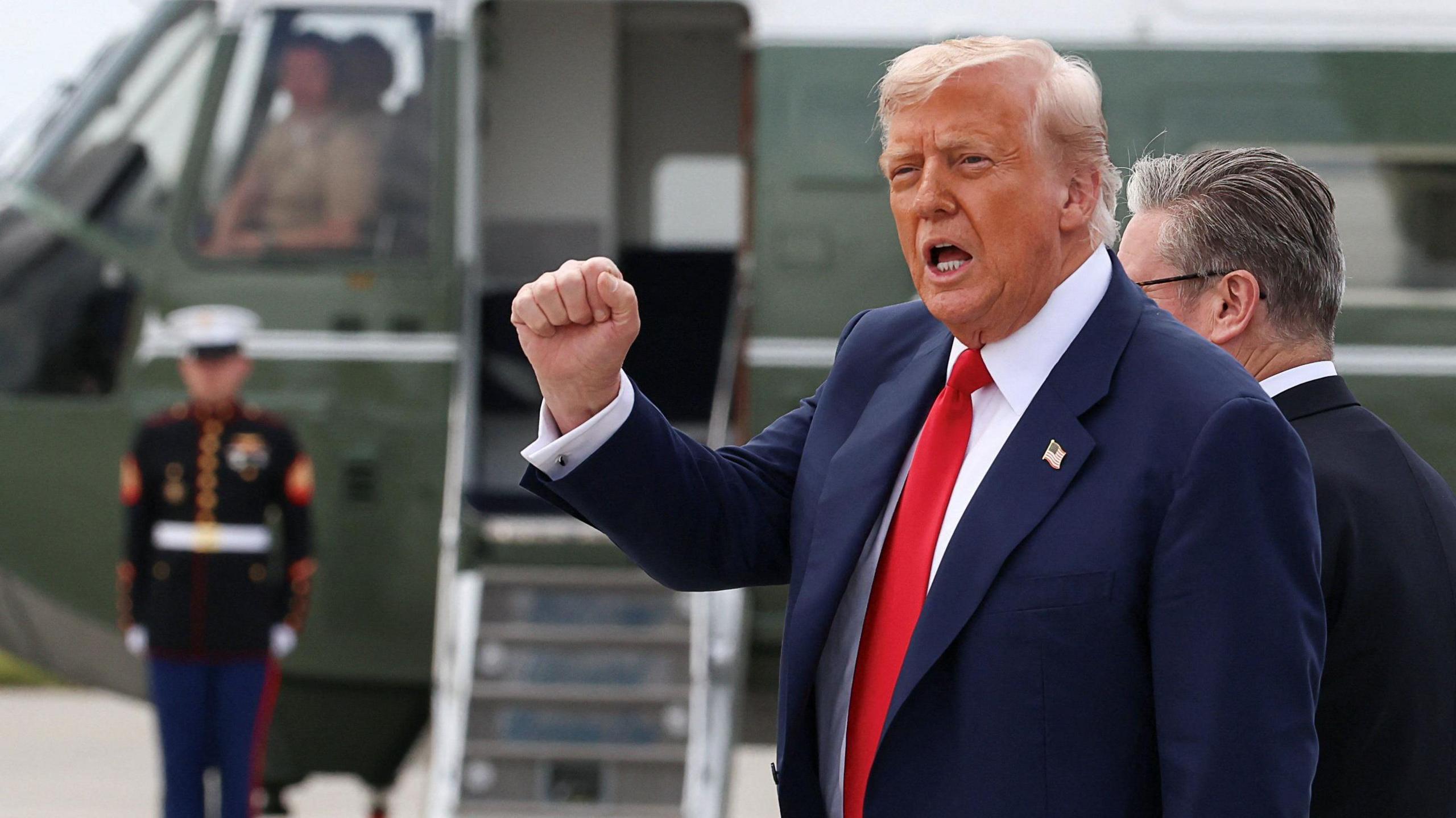 Donald trump ina suit and red tie pumps a fist in the air
