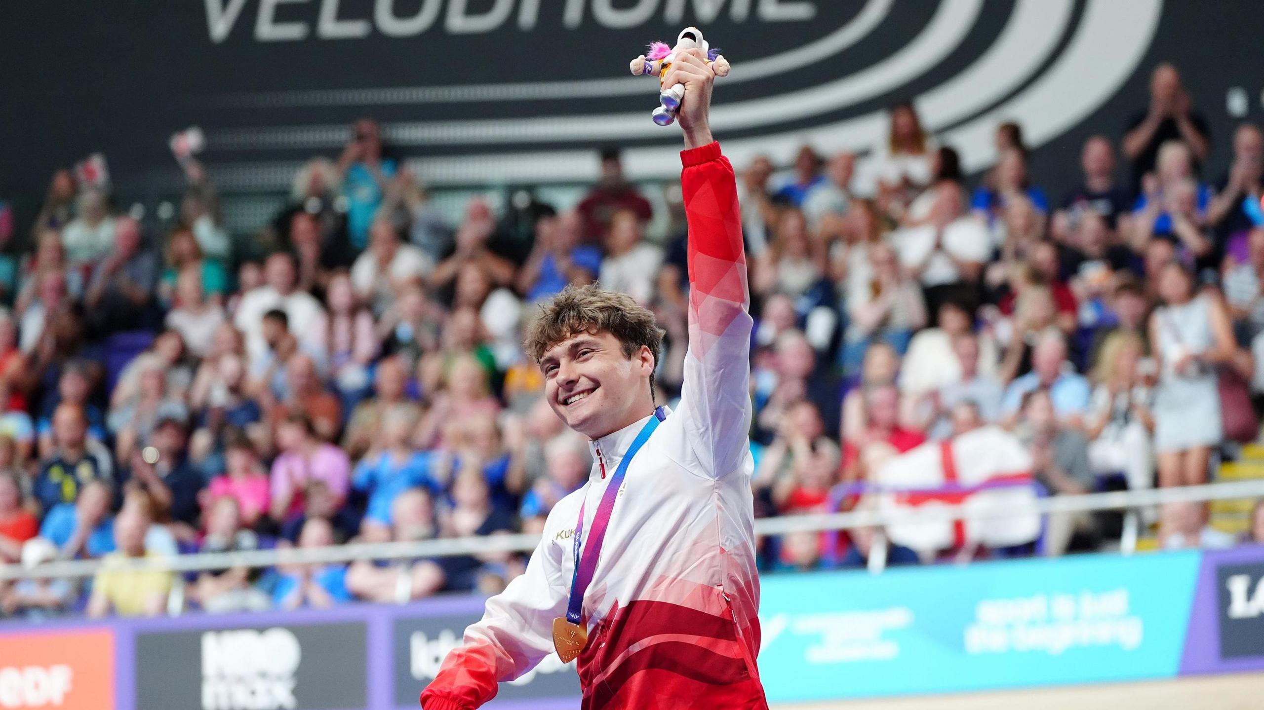 Matthew Robertson holds up his mascot with his gold medal around his neck at the Sir Chris Hoy Velodrome