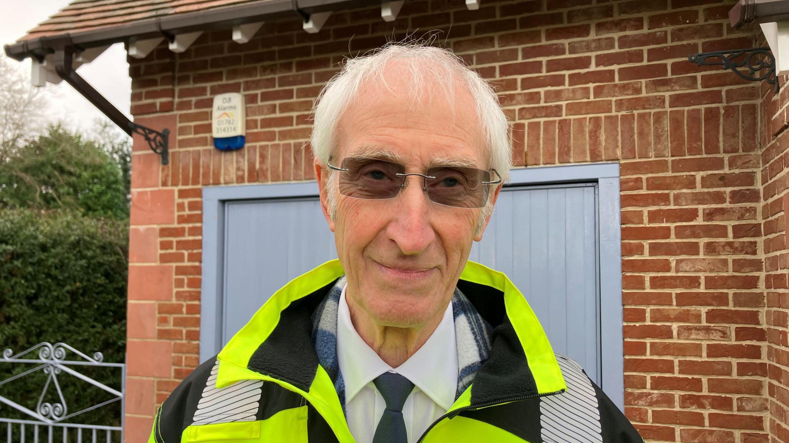 Pete Landon, 84, wearing a shirt and tie with sunglasses and a fluorescent jacket  