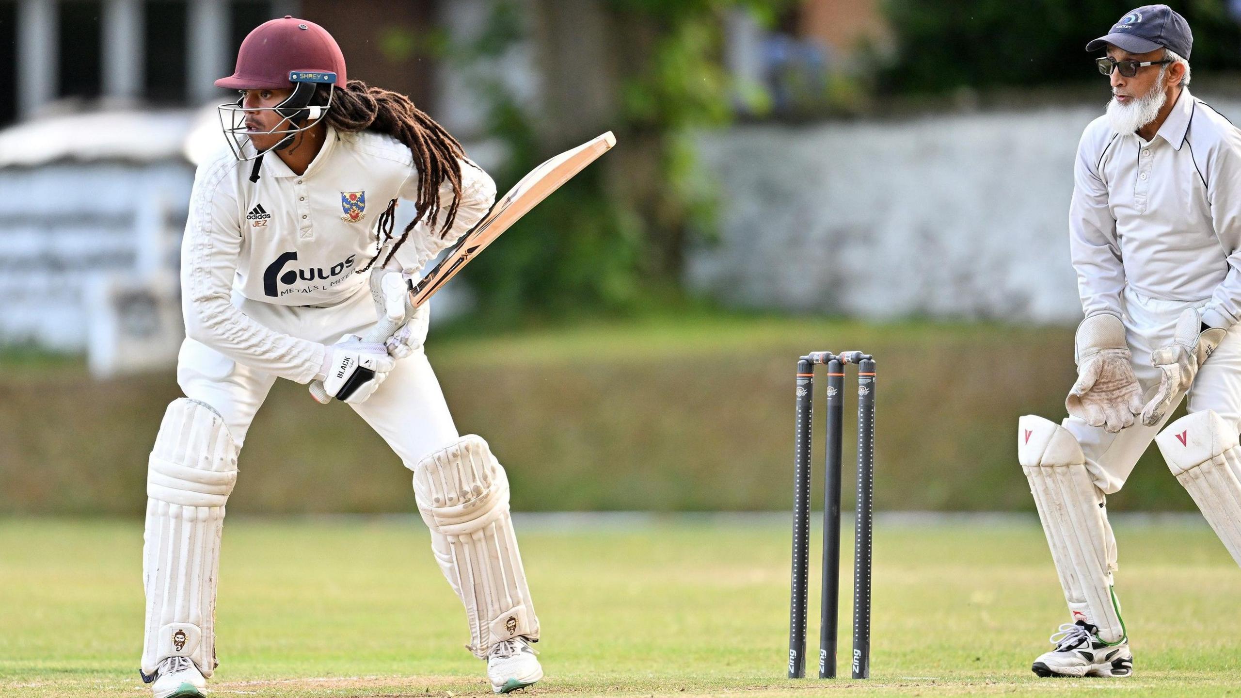 A batsman is poised for a delivery with a wicket-keeping imam looking on