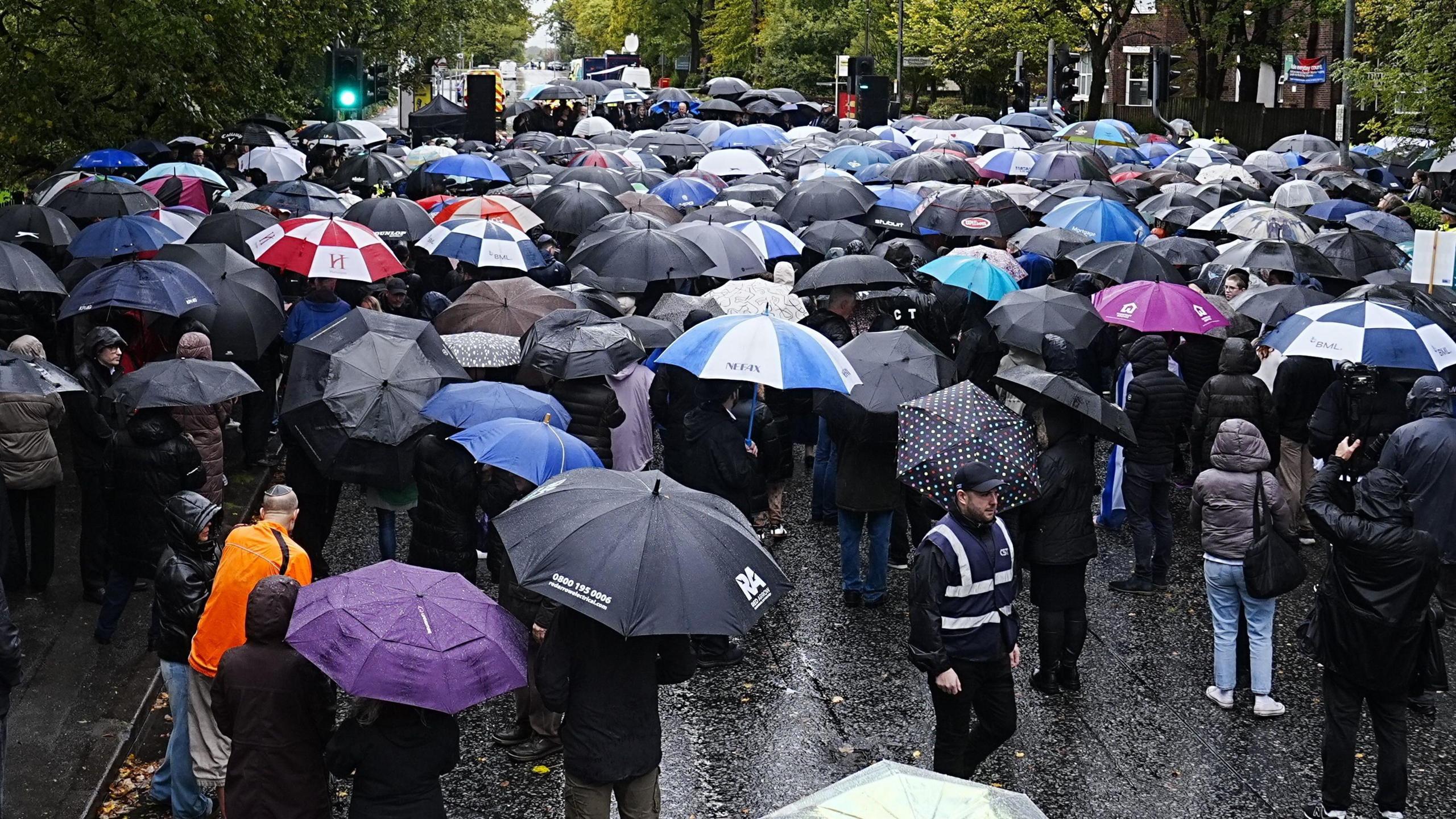 Hundreds of people attend vigil under their umbrellas. Picture shows the crowd at a junction with speakers in front.