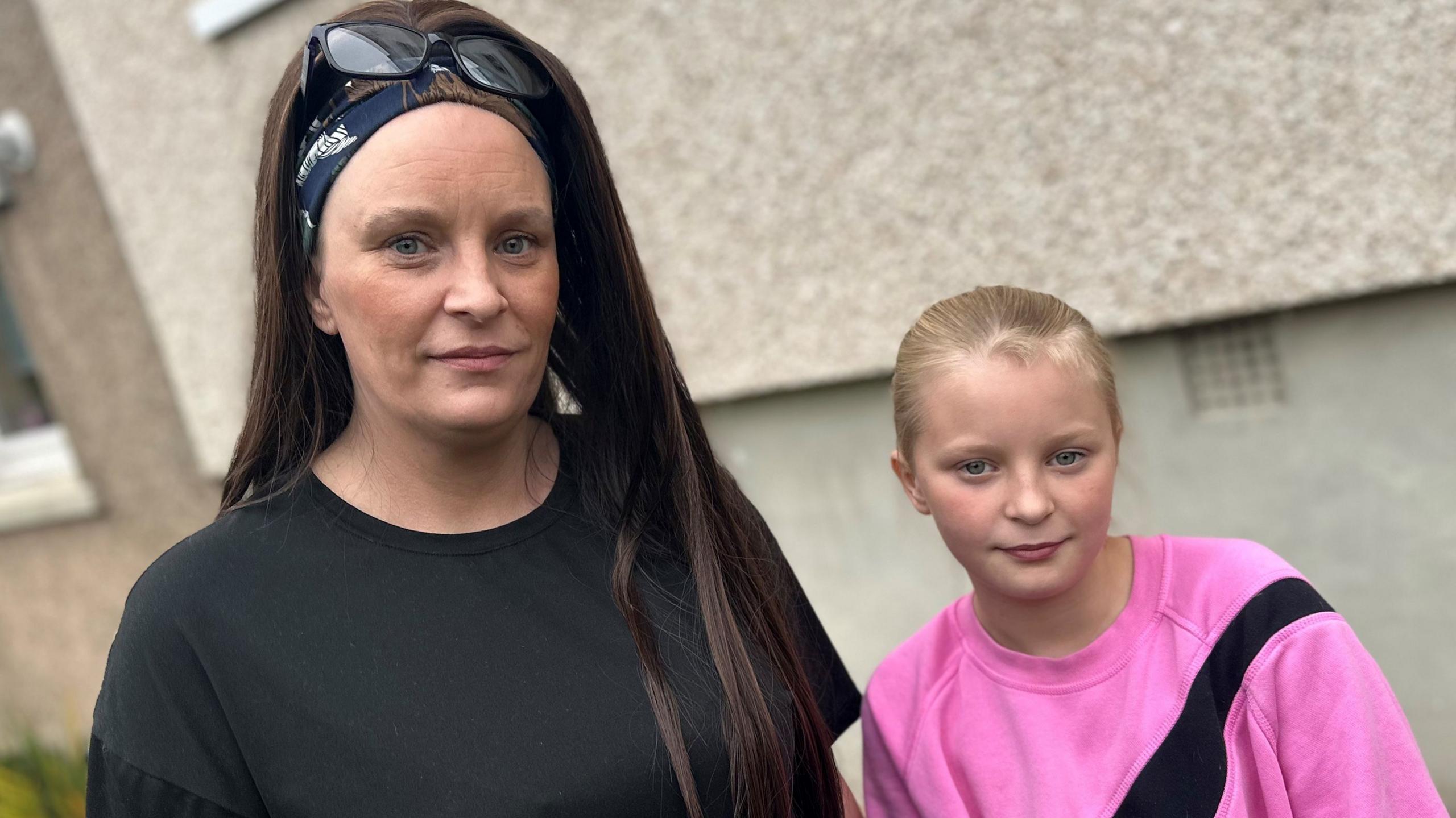 Michelle in a black top standing next to her daughter Devon, dressed in a pink top