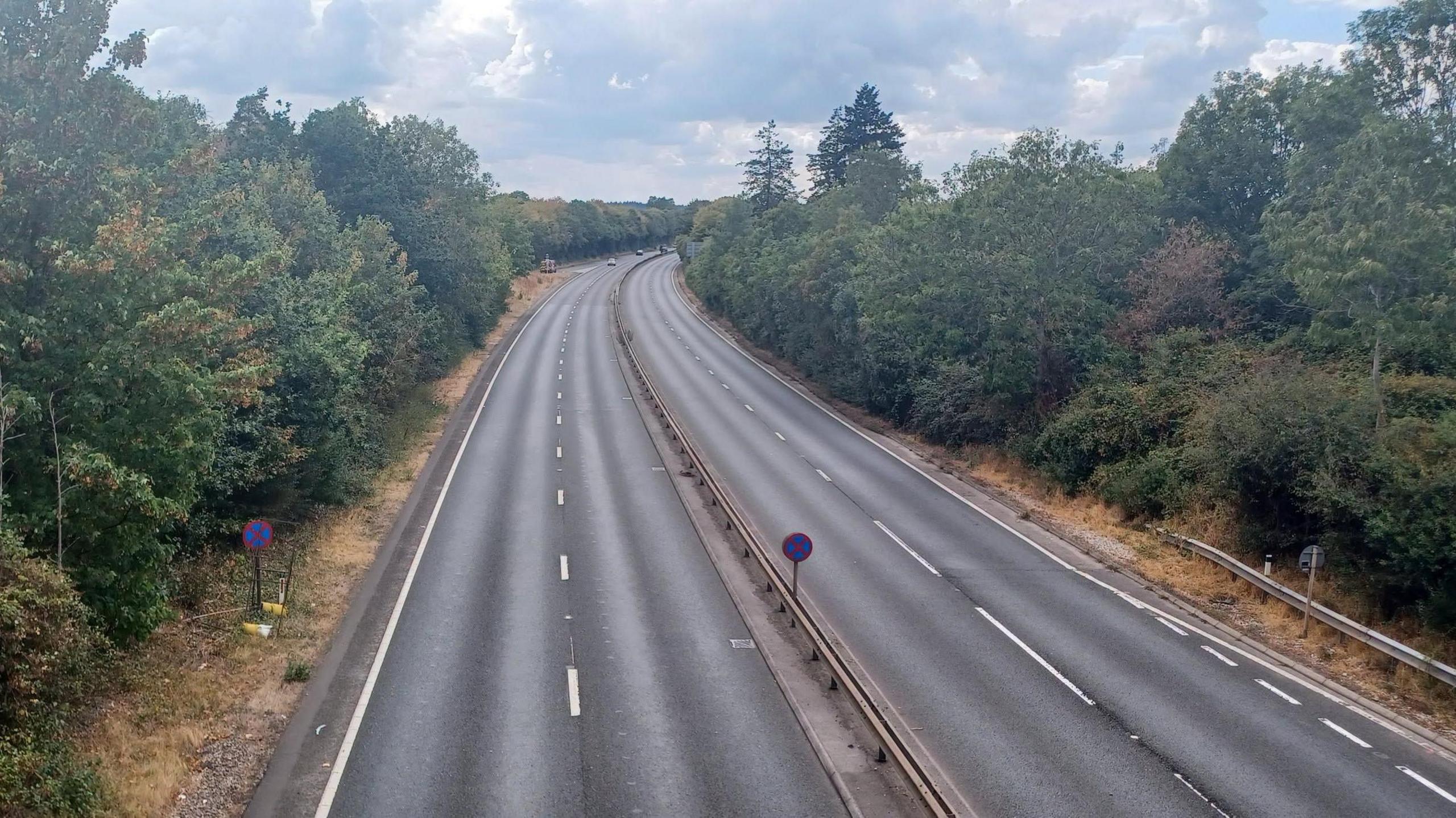 A deserted A31 dual carriageway lined with trees