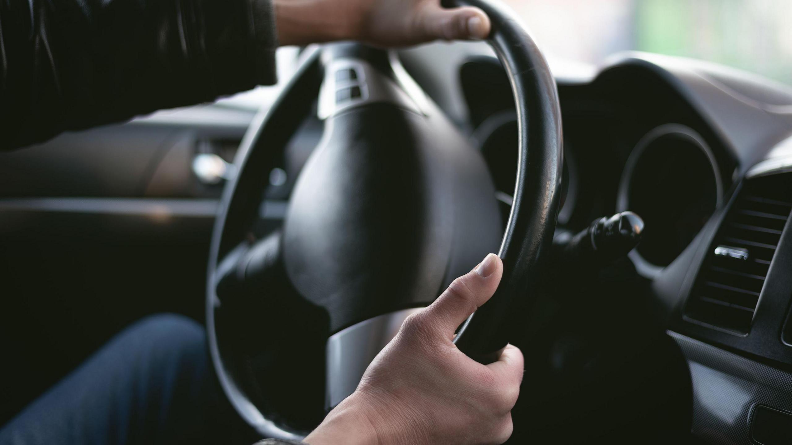 Generic photo of a man's hands on a driving wheel, steering the car.