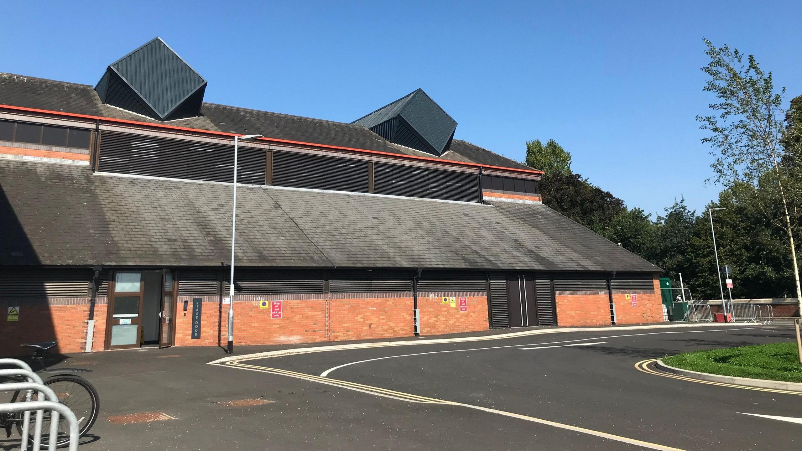 A large red-brick building with a tiled roof. 