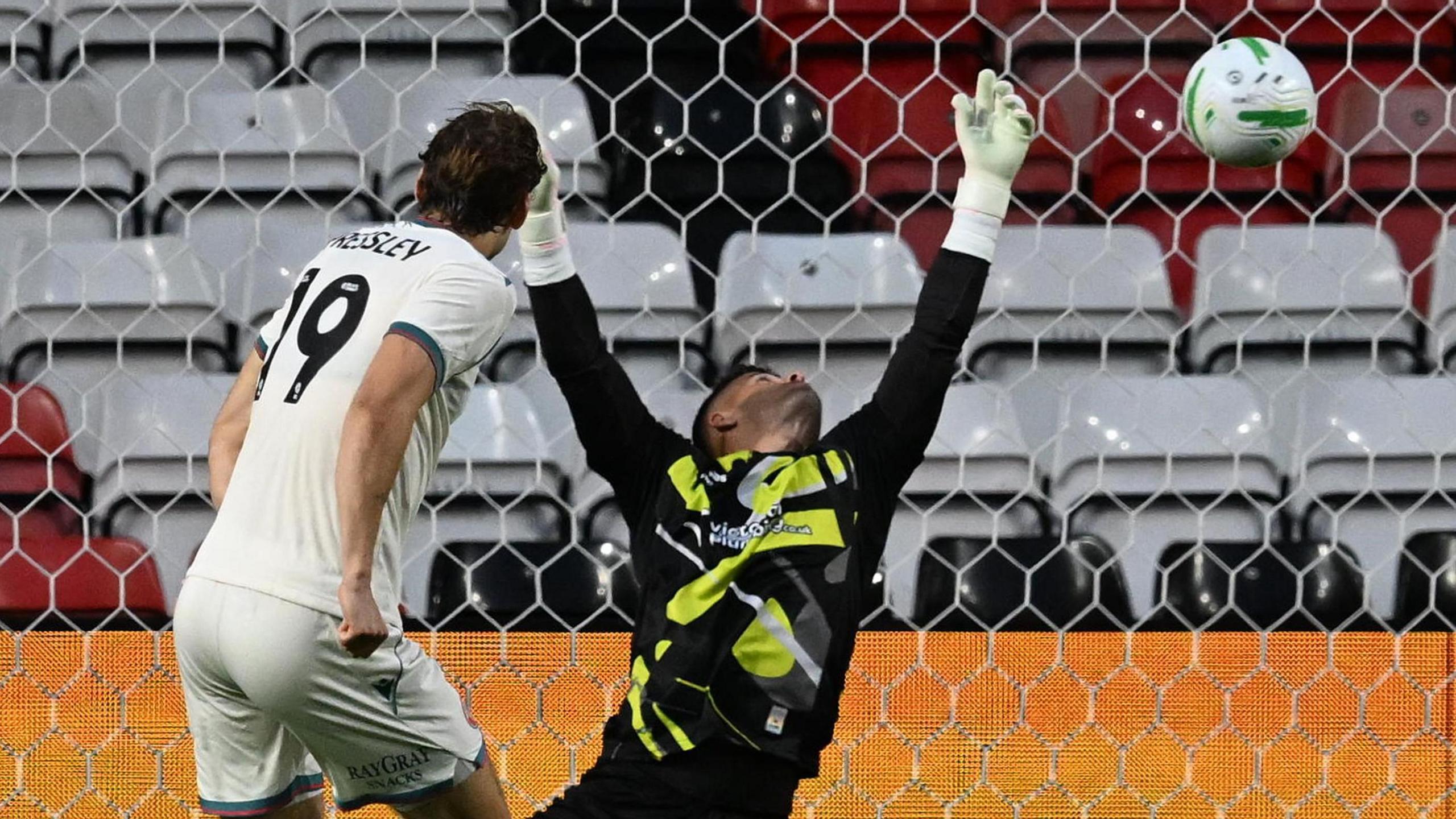 Bristol City goalkeeper Sam Tickle (right) stretches upwards in an attempt to save Aaron Pressley's goal-bound effort