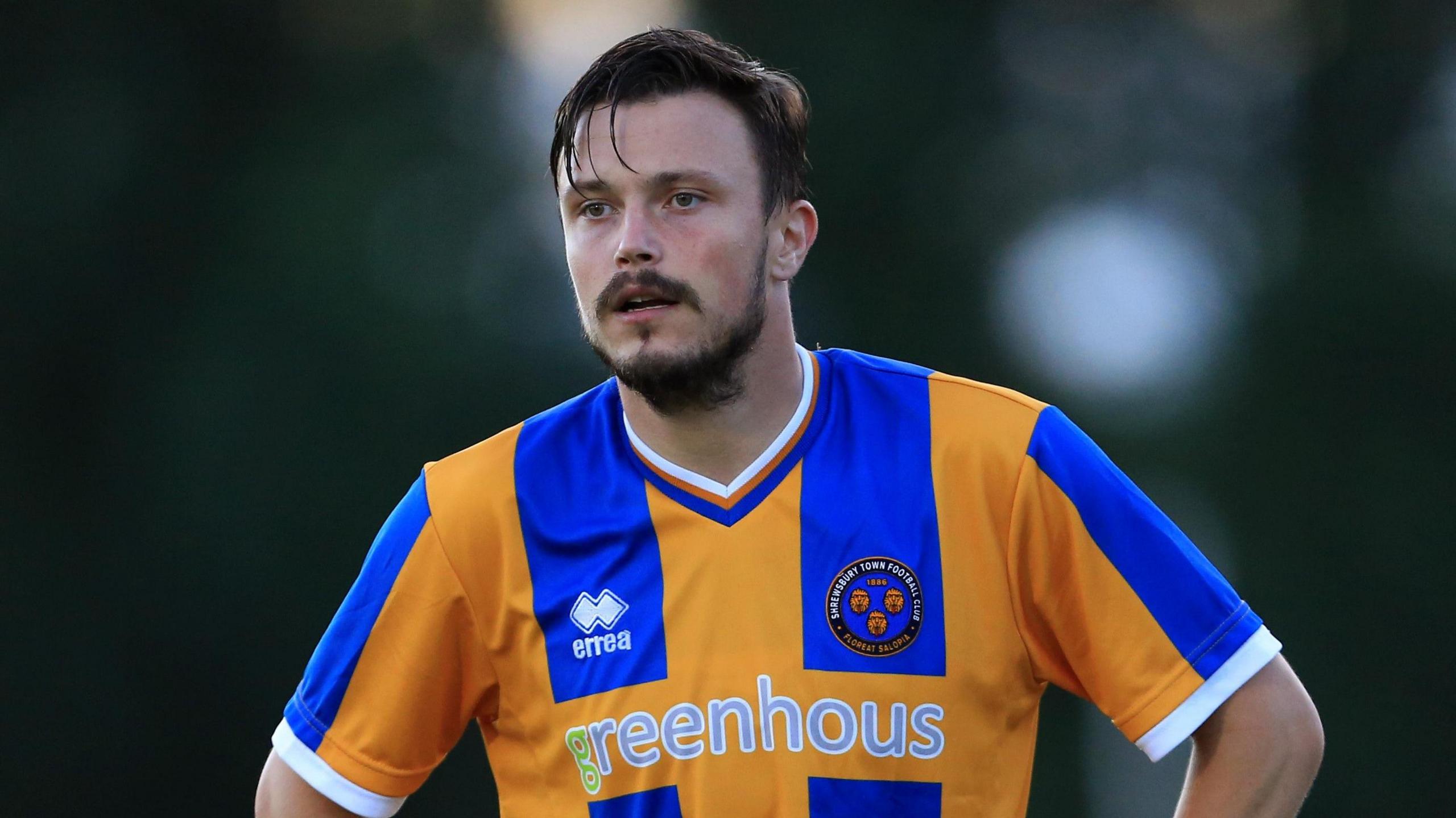 Andy Mangan, playing for Shrewsbury, stands with his hands on his hips and looks at something off camera