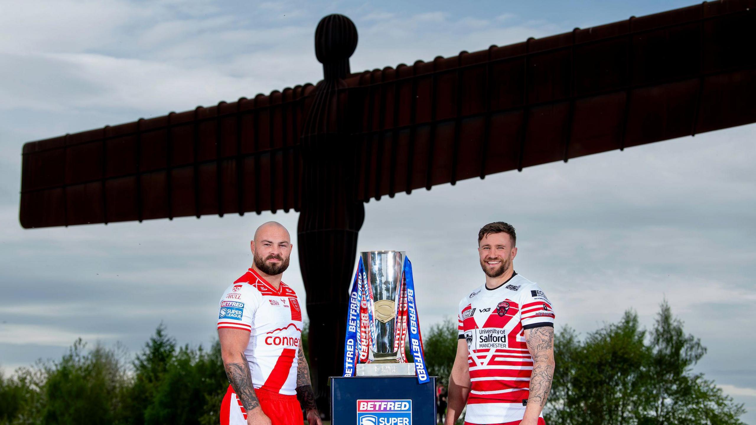 Hull KR's Sam Luckley and Salford Red Devils' Ben Hellewell stand aside the Super League Trophy in front of the Angel of the North