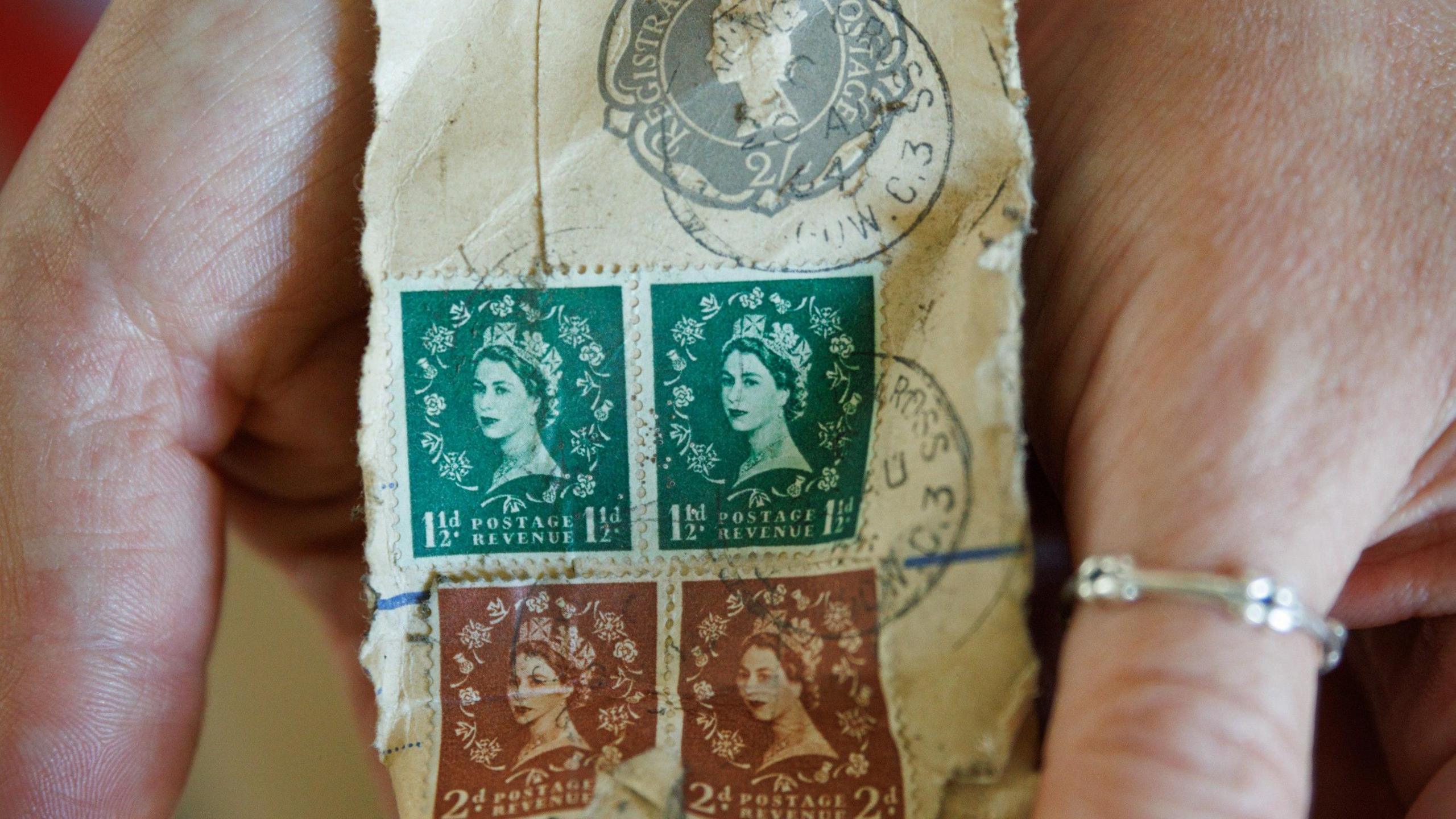 A close-up of four stamps. Two are green and two are red, they both have Queen Elizabeth II and the words "postage revenue" on them. The green one is valued at 1 1/2d and the red is valued at 2d. 