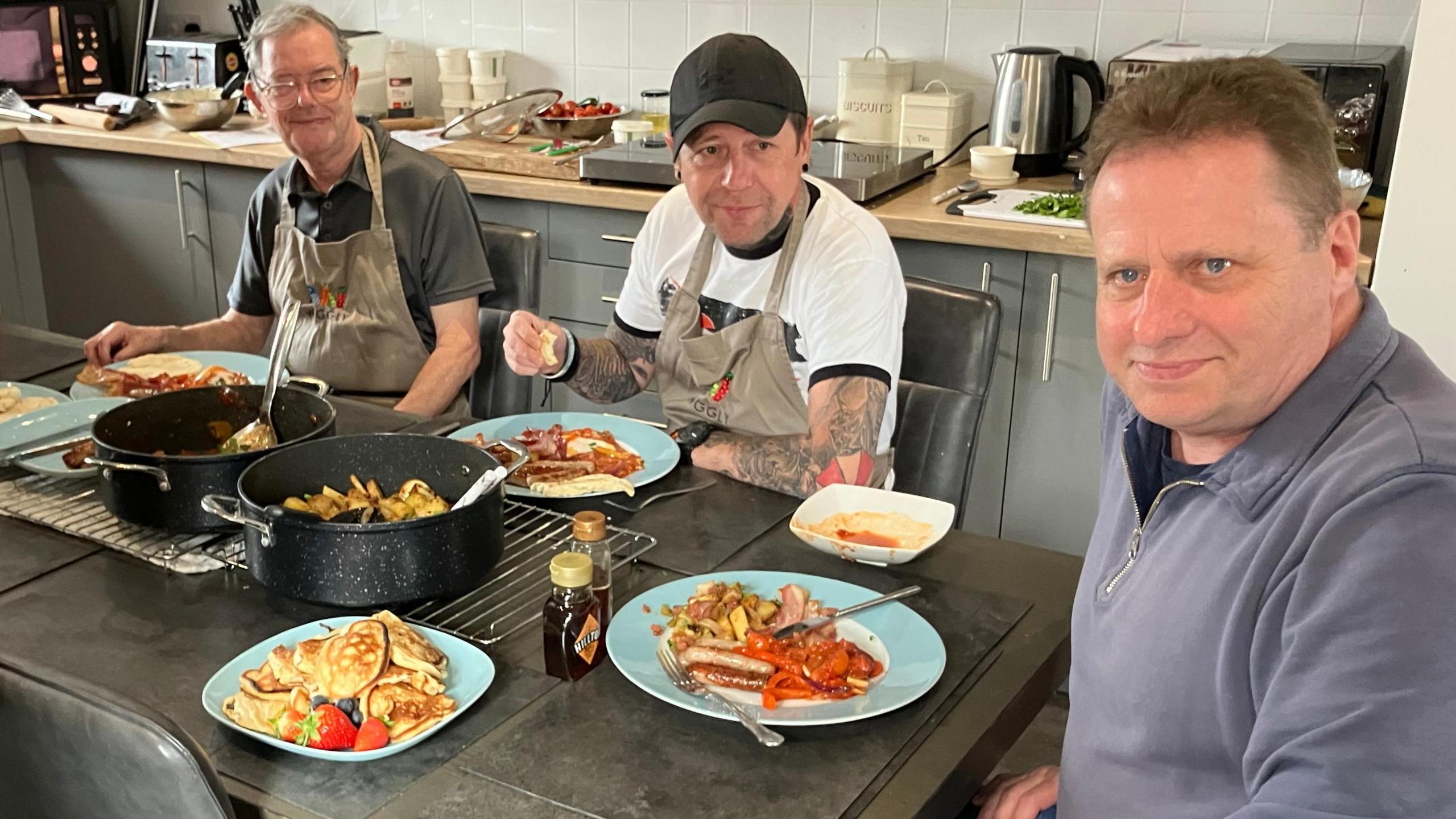 A group of veterans around a kitchen table learning cooking skills.