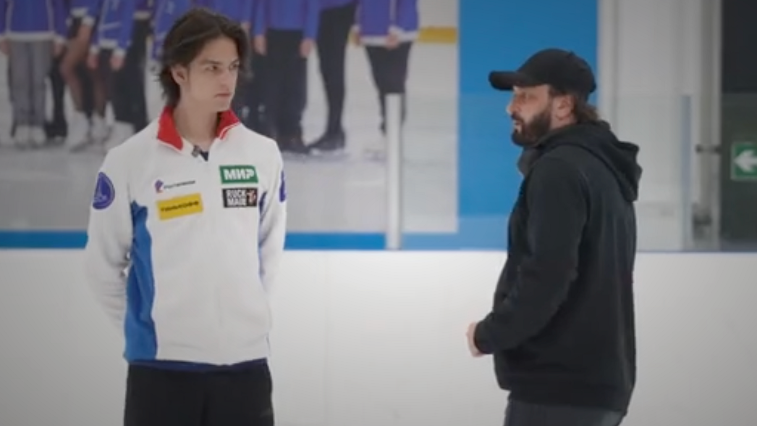 Petr Gummenik and Ilya Averbukh standing together on an ice rink in sports attire
