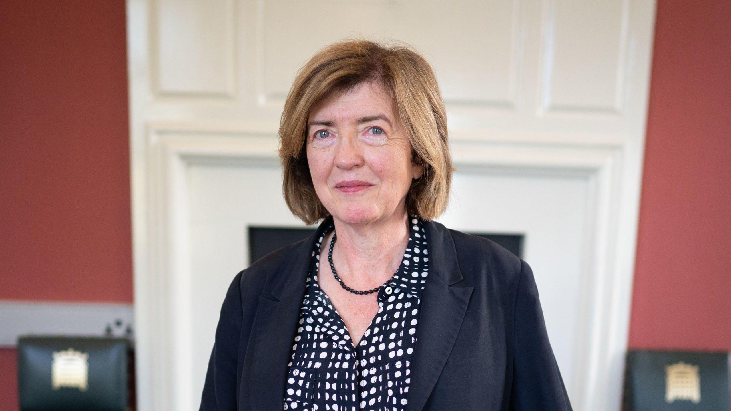 Sue Gray poses for a picture placing her hands on a chair below her