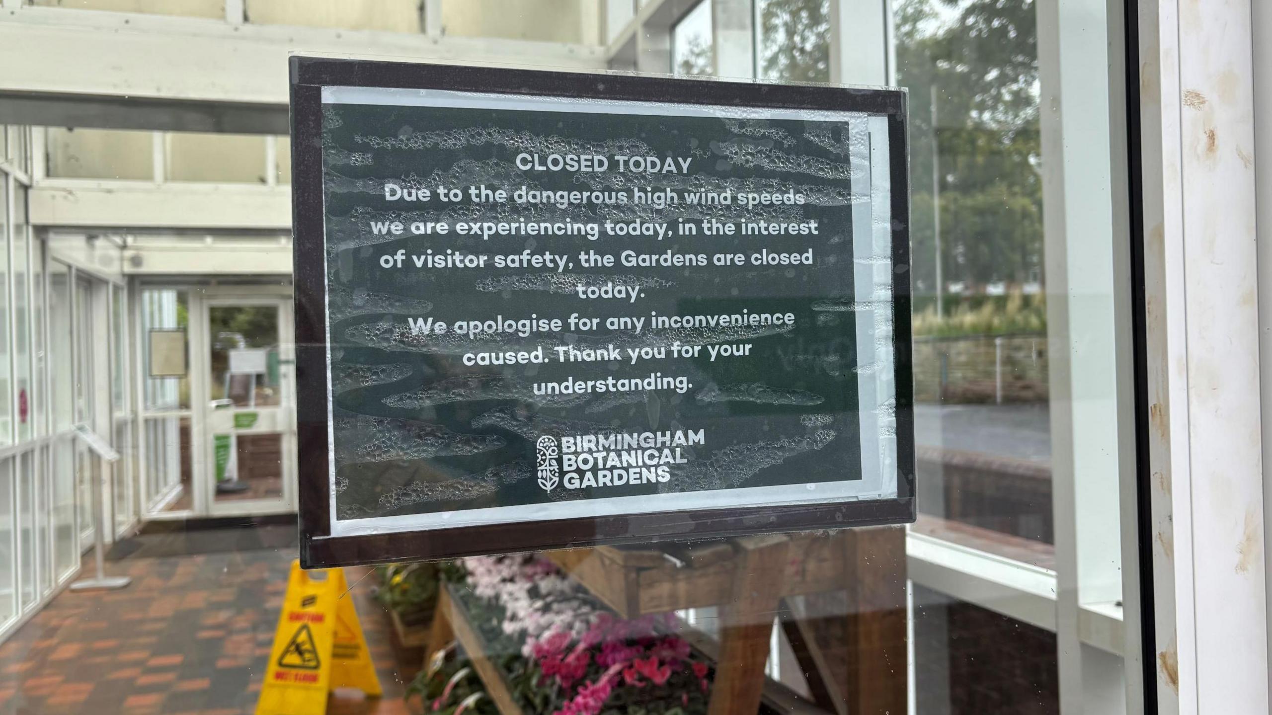 A sign in black with white writing which says "due to the dangerous high wind speeds we are experiencing today, in the interest of visitor safety, the gardens are closed today. We apologise for any inconvenience caused. Thank you for your understanding. 